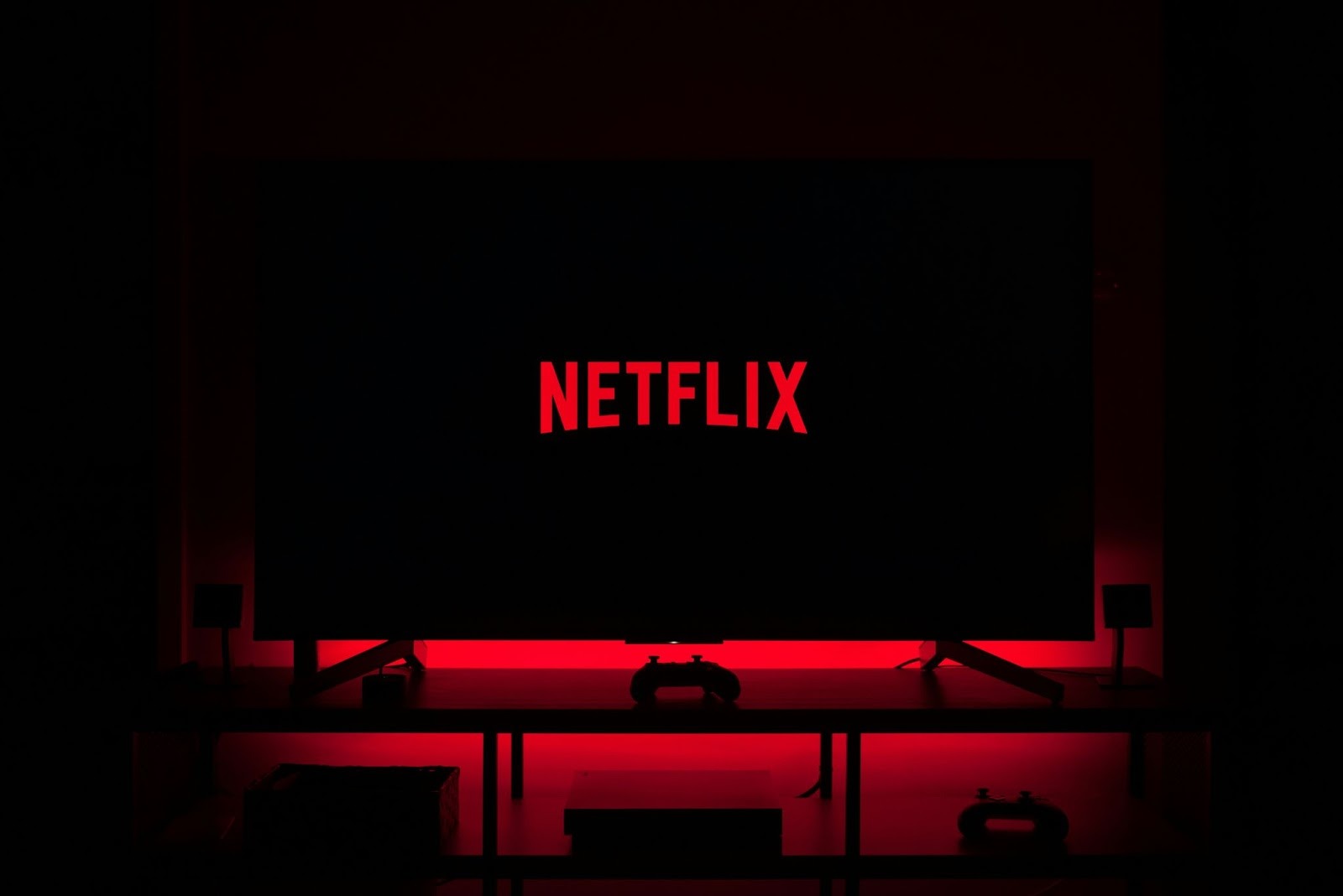 Netflix wordmark displayed in red on a television in a dark room.