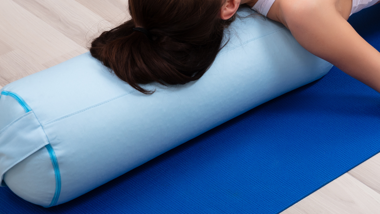 Person resting on a light blue yoga bolster