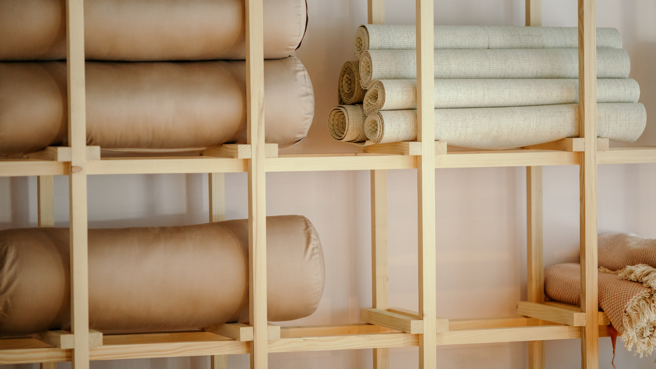 Wooden shelves holding yoga mats and bolsters