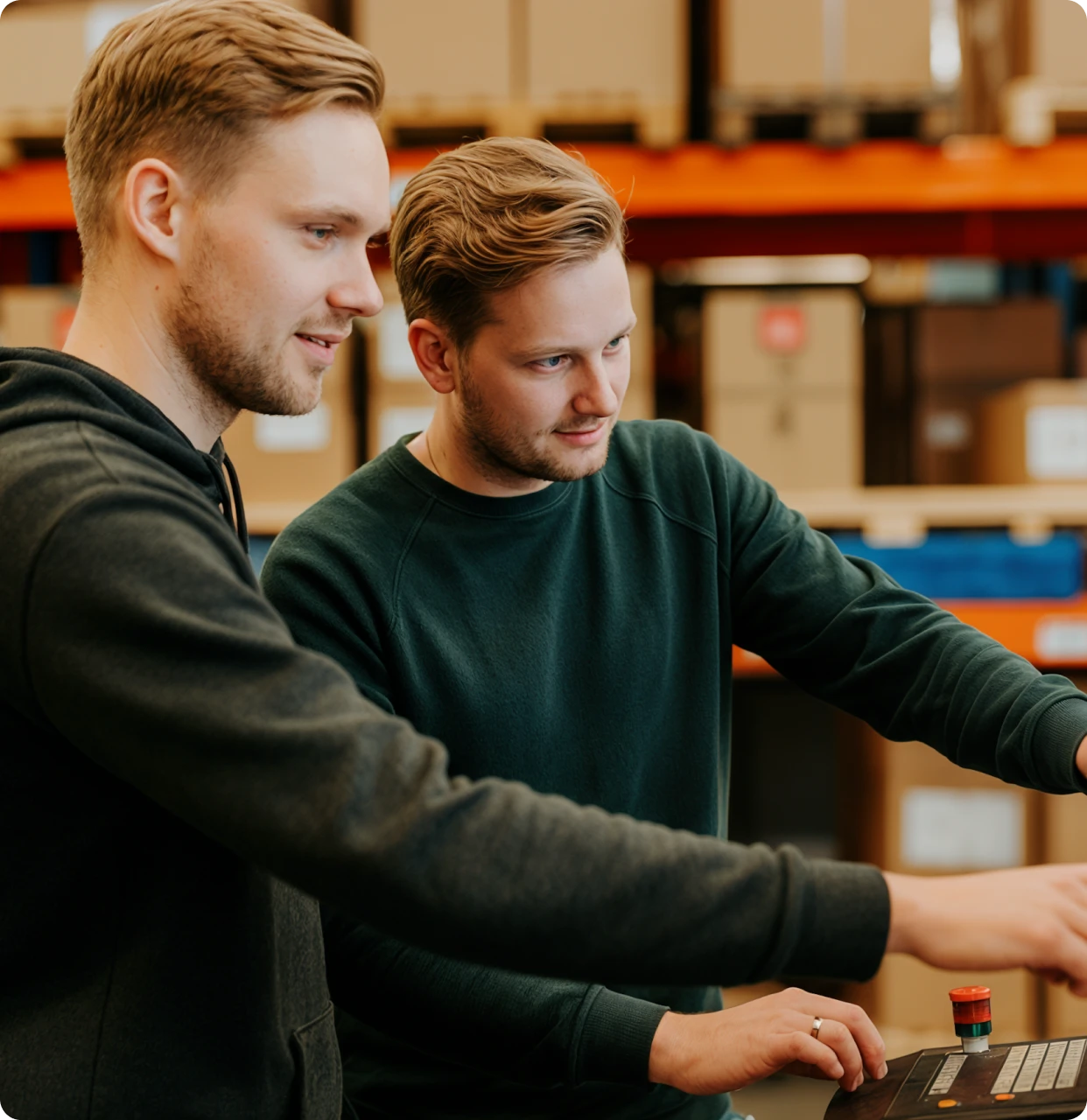Two men looking at a computer screen in a warehouse.