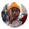 Person wearing a yellow knit hat and a dark patterned scarf, looking towards the camera.