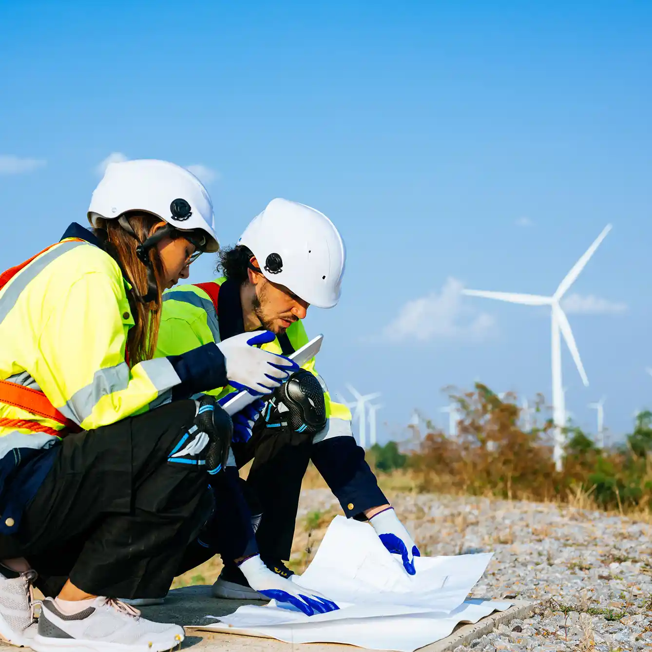 Two People Crouched At Wind Farm Site In High Vis and Hard Hats Preparing An Environmental Impact Assessment