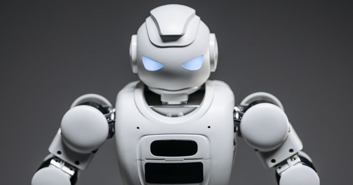 Advanced white humanoid robot with blue LED eyes on grey background