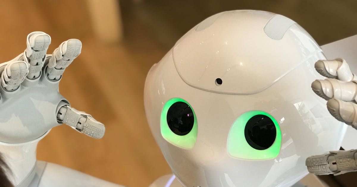 Pepper robot with glowing green eyes and hands close-up