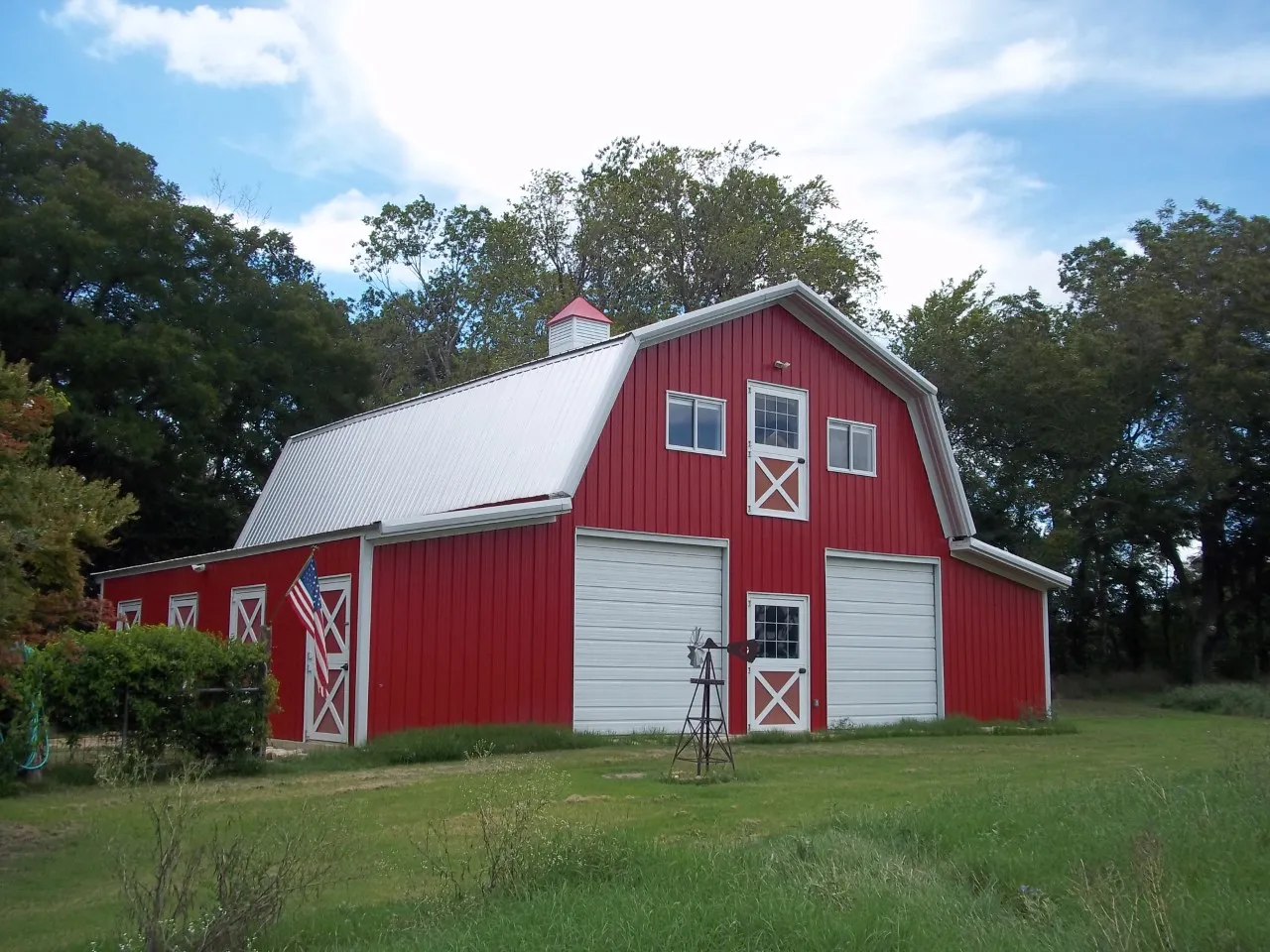 Red steel barn with white trim and two large garage doors