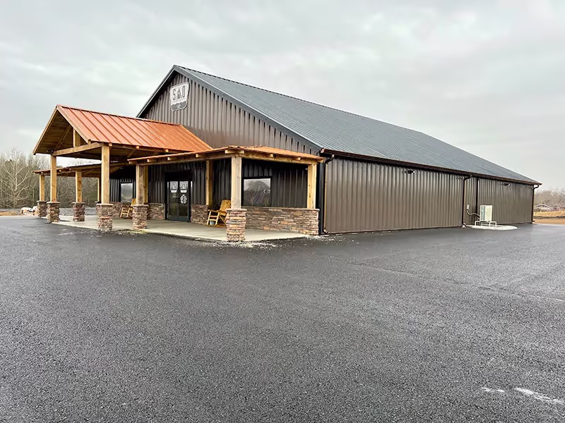 Large brown steel commercial building with stone pillars and a wooden overhang