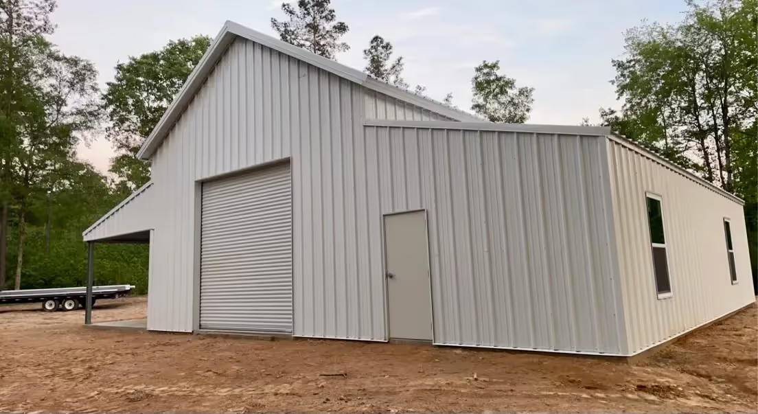 Large white steel barn with a roll-up door and a pedestrian door