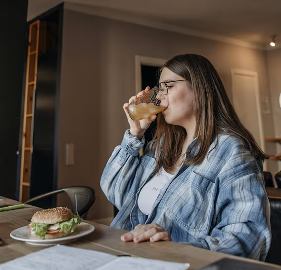 Woman in glasses drinking a beverage at a table with a sandwich in front of her and a graphic showing A1C levels decreased by 0.8%.