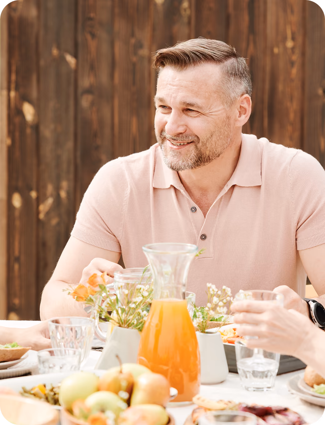 Smiling woman in a blue shirt sitting at a table with bowls of soup and salad.
