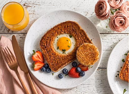 Plate with toast holding a fried egg, toasted English muffin, strawberries, blueberries, and a glass of orange juice.