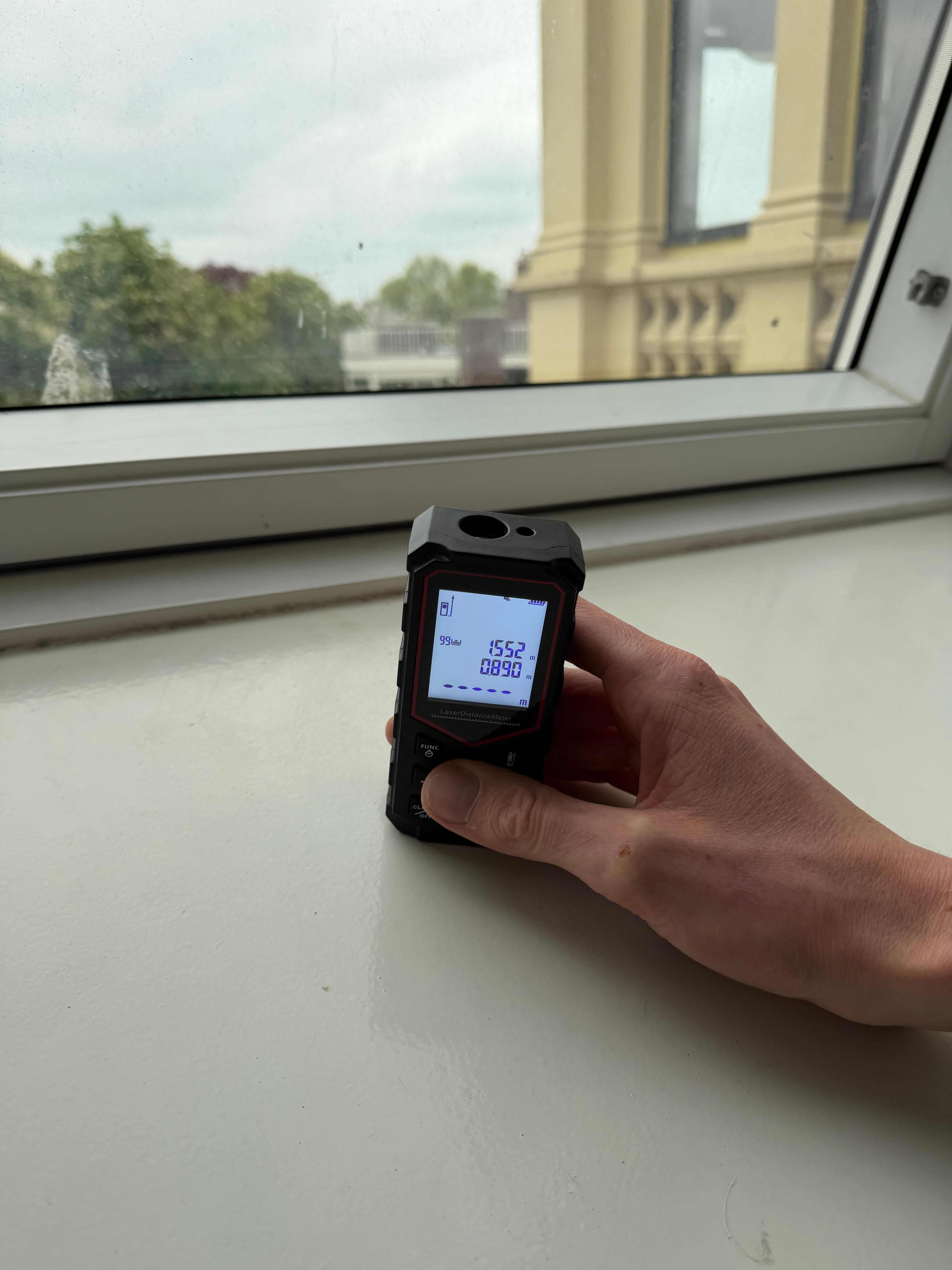Lasermeter op een vensterbank tijdens het inmeten van een woning