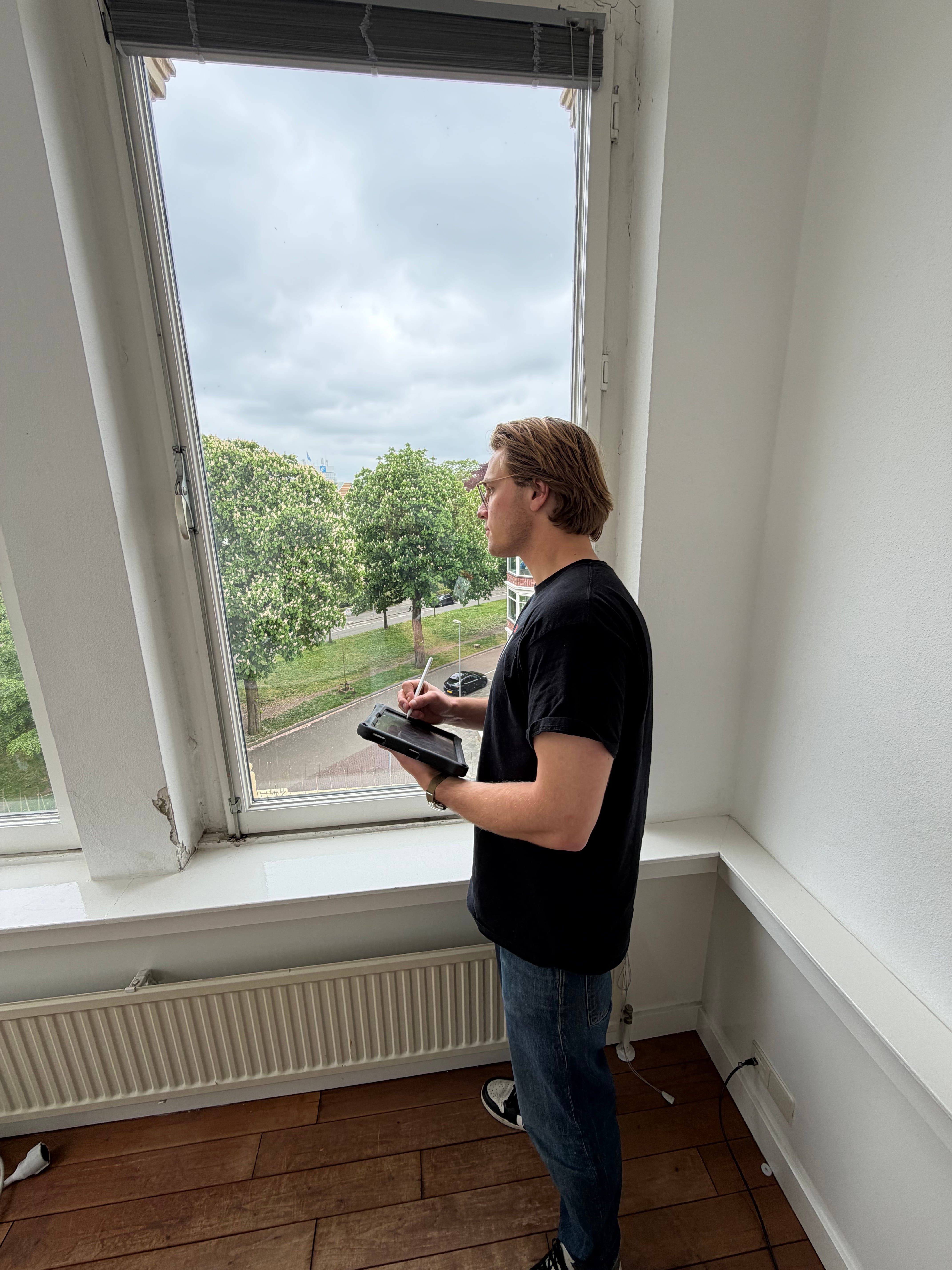 Adviseur van Energie-Lab neemt met een tablet een woning op bij het raam