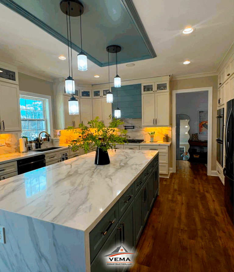 Modern kitchen with marble island countertop, pendant lights, white and blue cabinetry, and wooden floor.