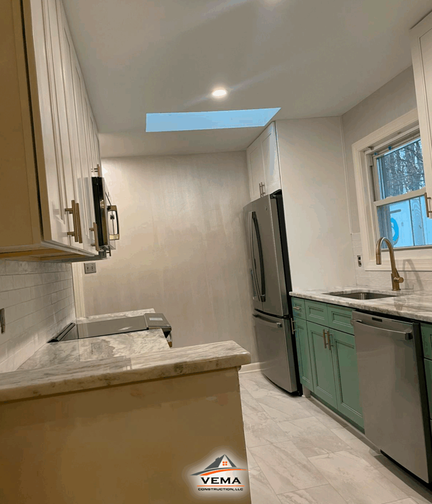 Modern kitchen with white upper cabinets, green lower cabinets, marble countertops, stainless steel appliances, and a skylight in the ceiling.