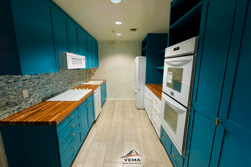 Modern galley kitchen with teal cabinets, wooden countertops, white appliances, and a mosaic tile backsplash.