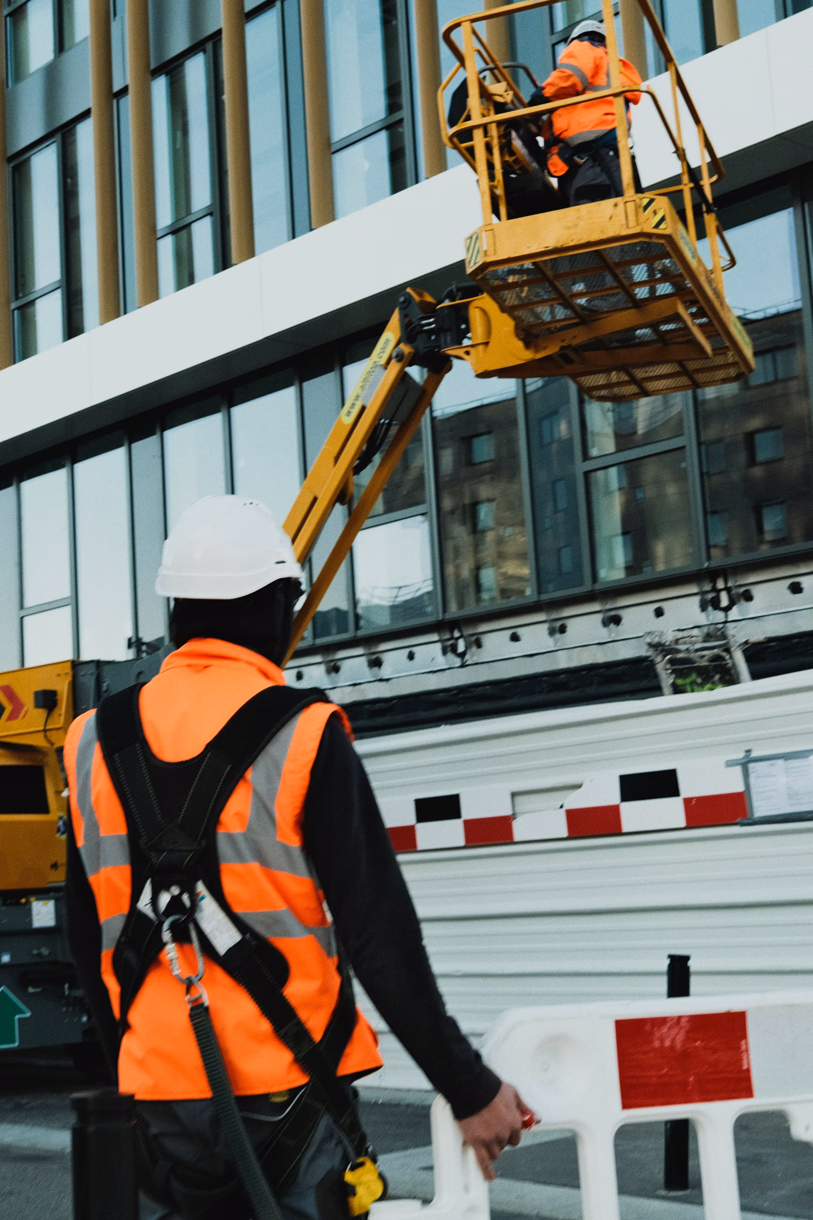 A construction professional wearing a safety harness and hard hat operating an aerial lift, representing TrueSpan Group’s focus on workplace safety and Workers’ Comp advocacy.