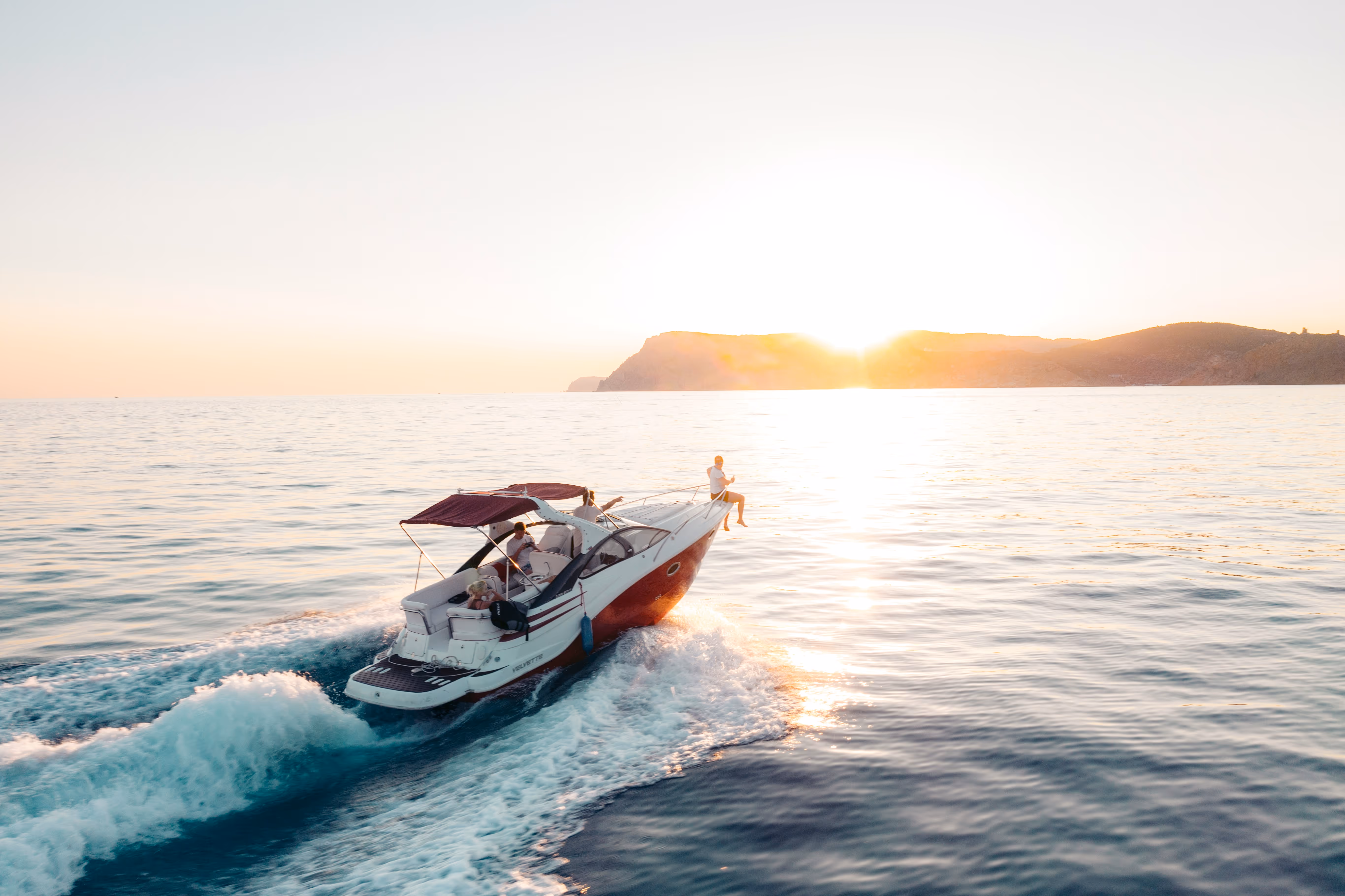 Exterior view of a luxurious motorboat moving through open water at sunset, illustrating TrueSpan Group’s specialized high-value watercraft and marine insurance.