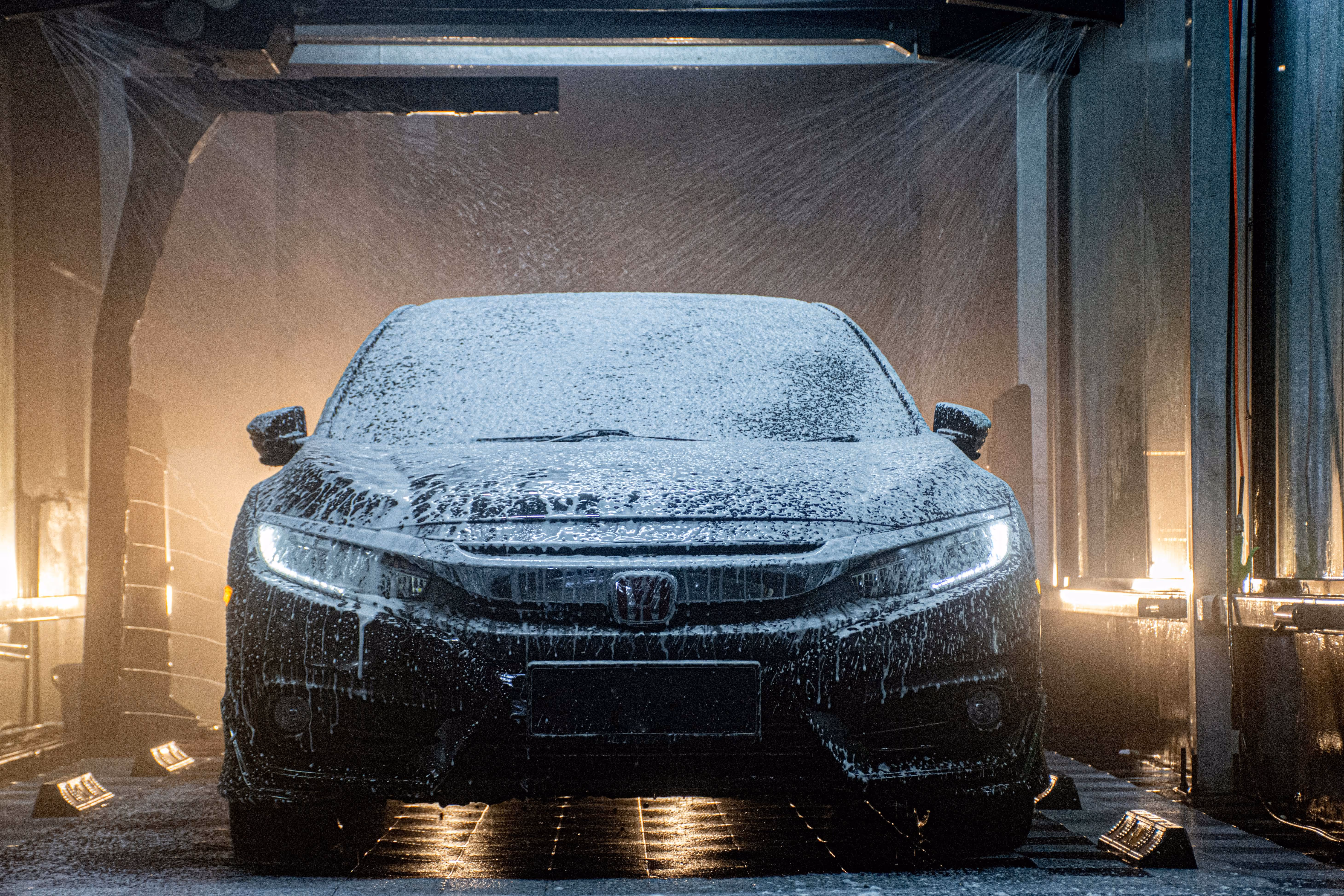 A vehicle going through an automated car wash tunnel with high-pressure soap application, illustrating equipment breakdown and garagekeepers liability