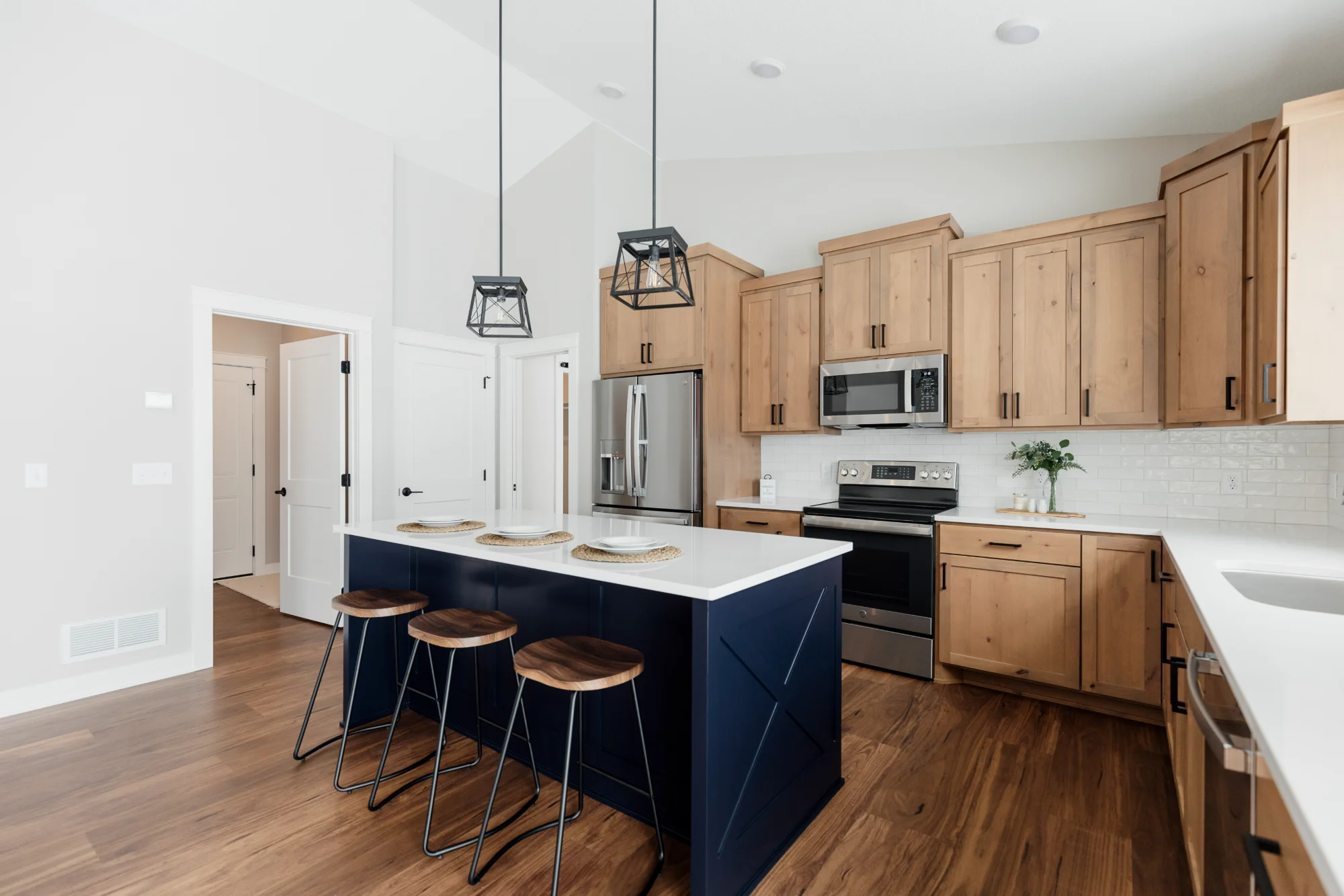 Kitchen with navy island, pendant lights, and stainless appliances