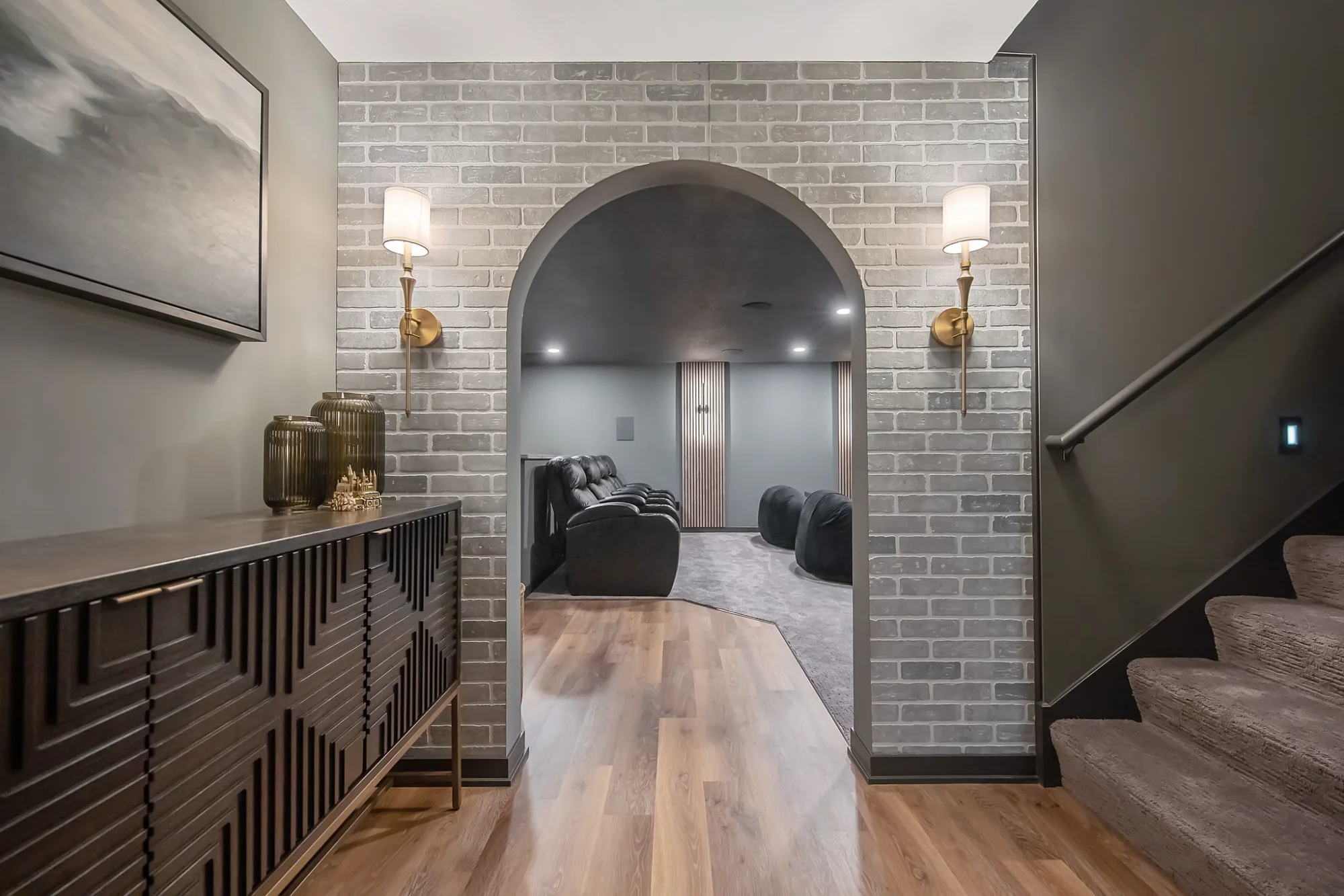 Hallway with console table, arched doorway, and brick wall