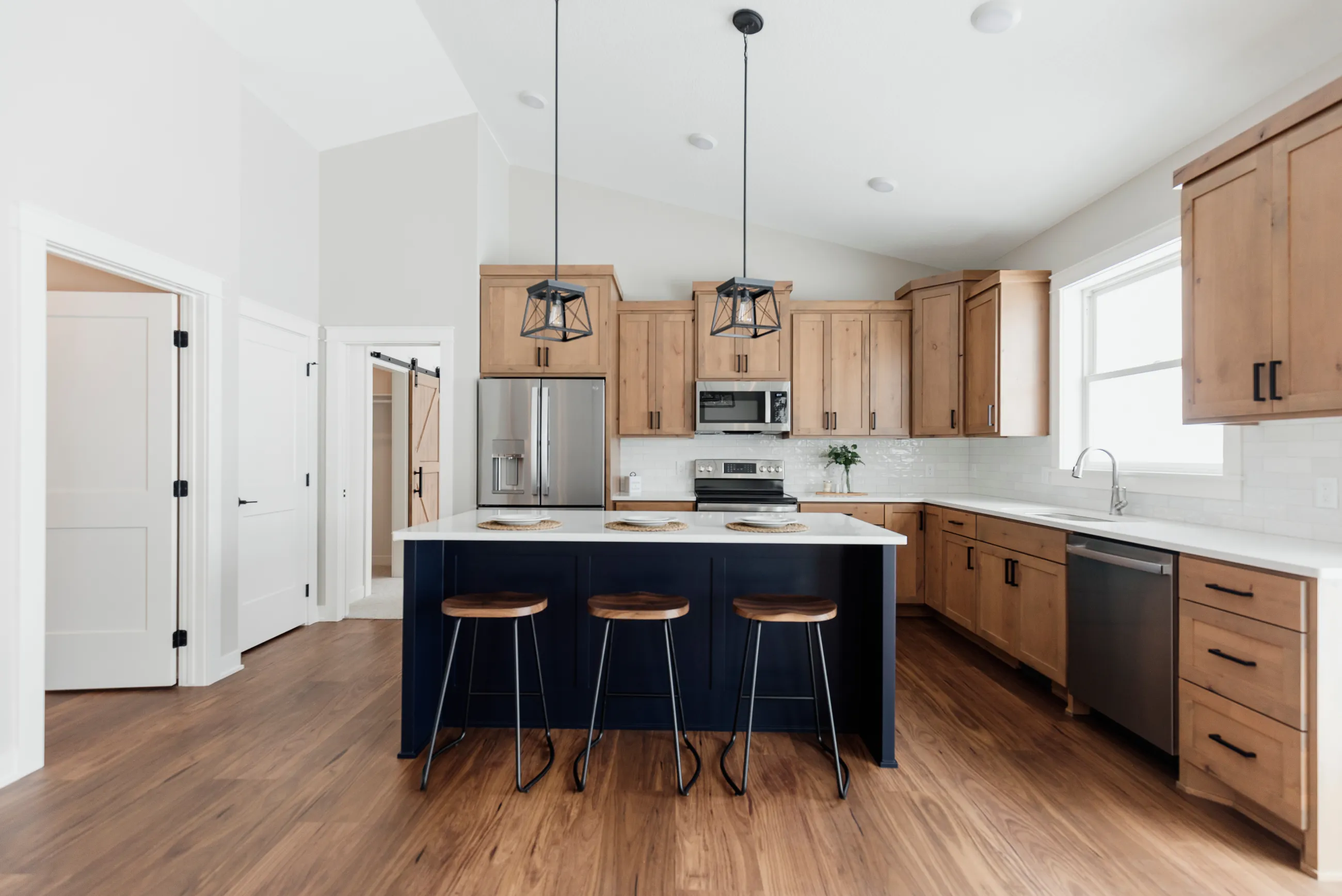 Modern kitchen with black island, stools, and wood cabinets