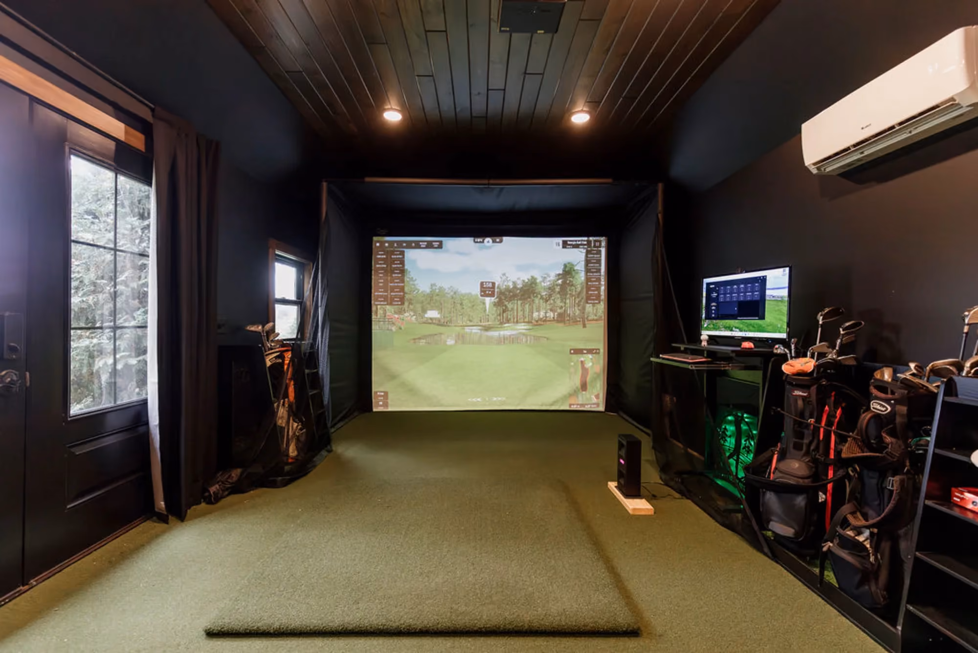 Indoor golf simulator room with turf and projection screen