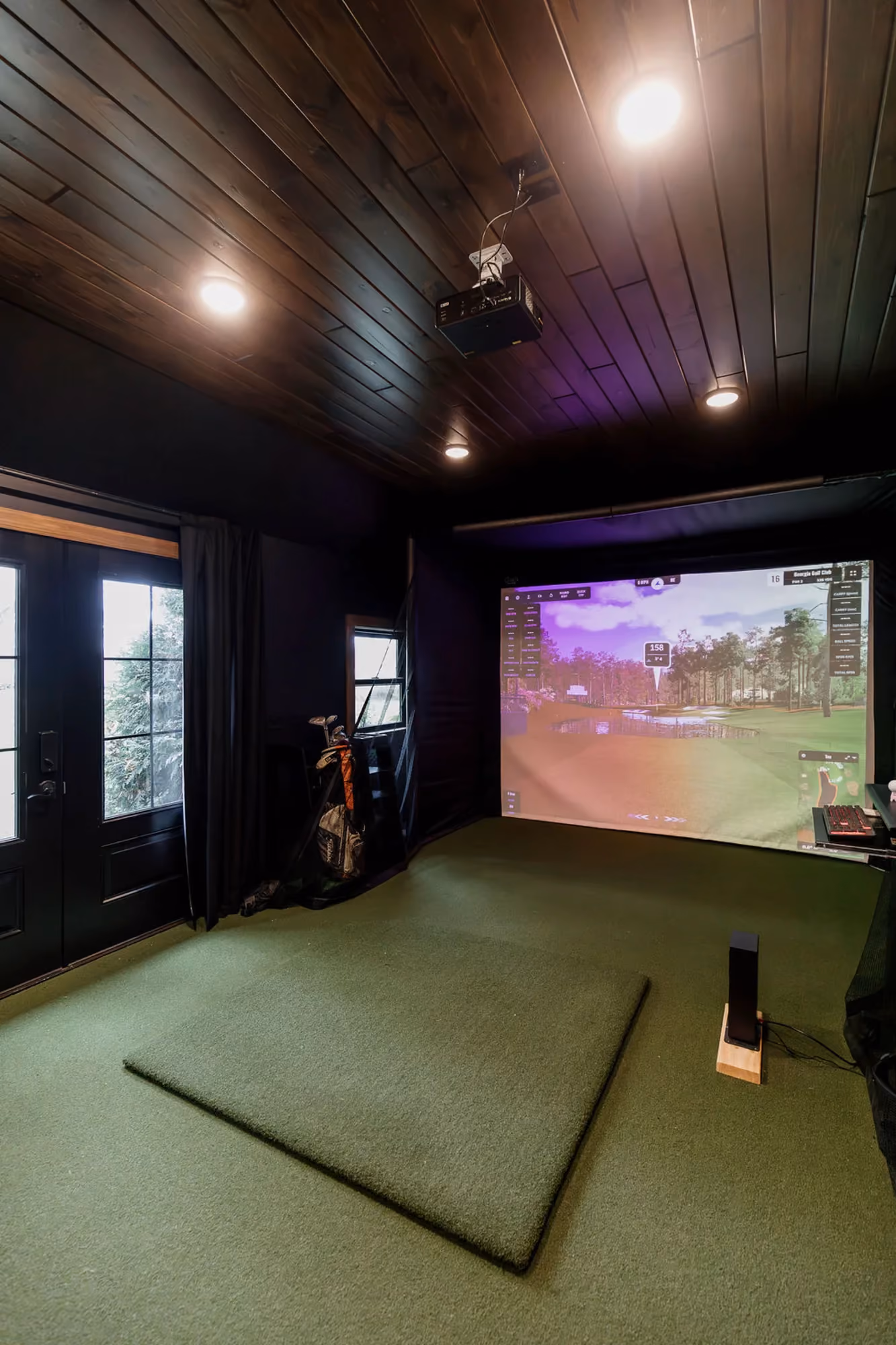 Golf simulator room with mat and screen