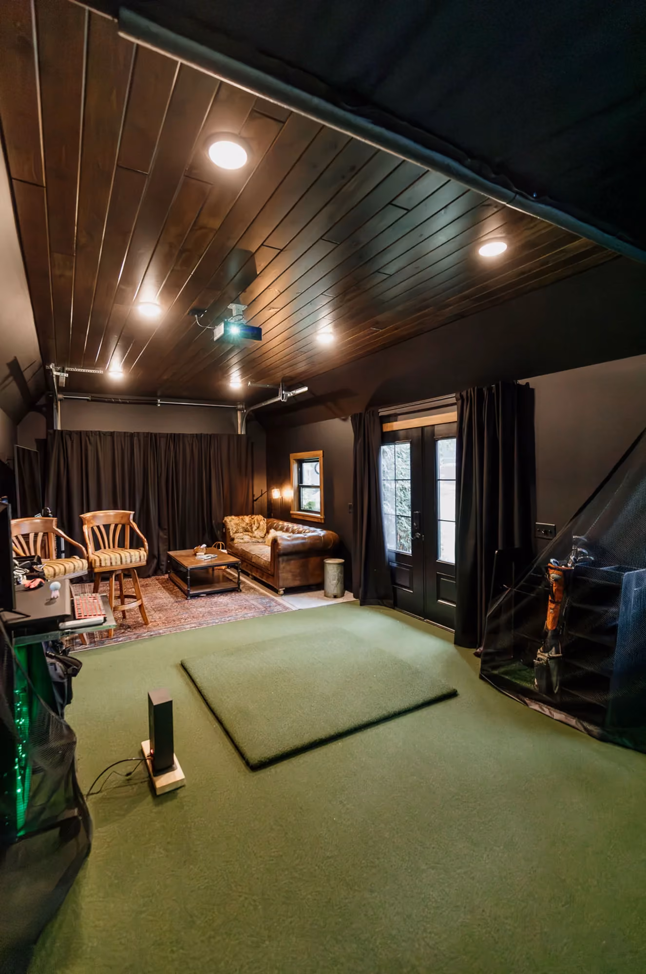 Golf simulator room with green turf and screen