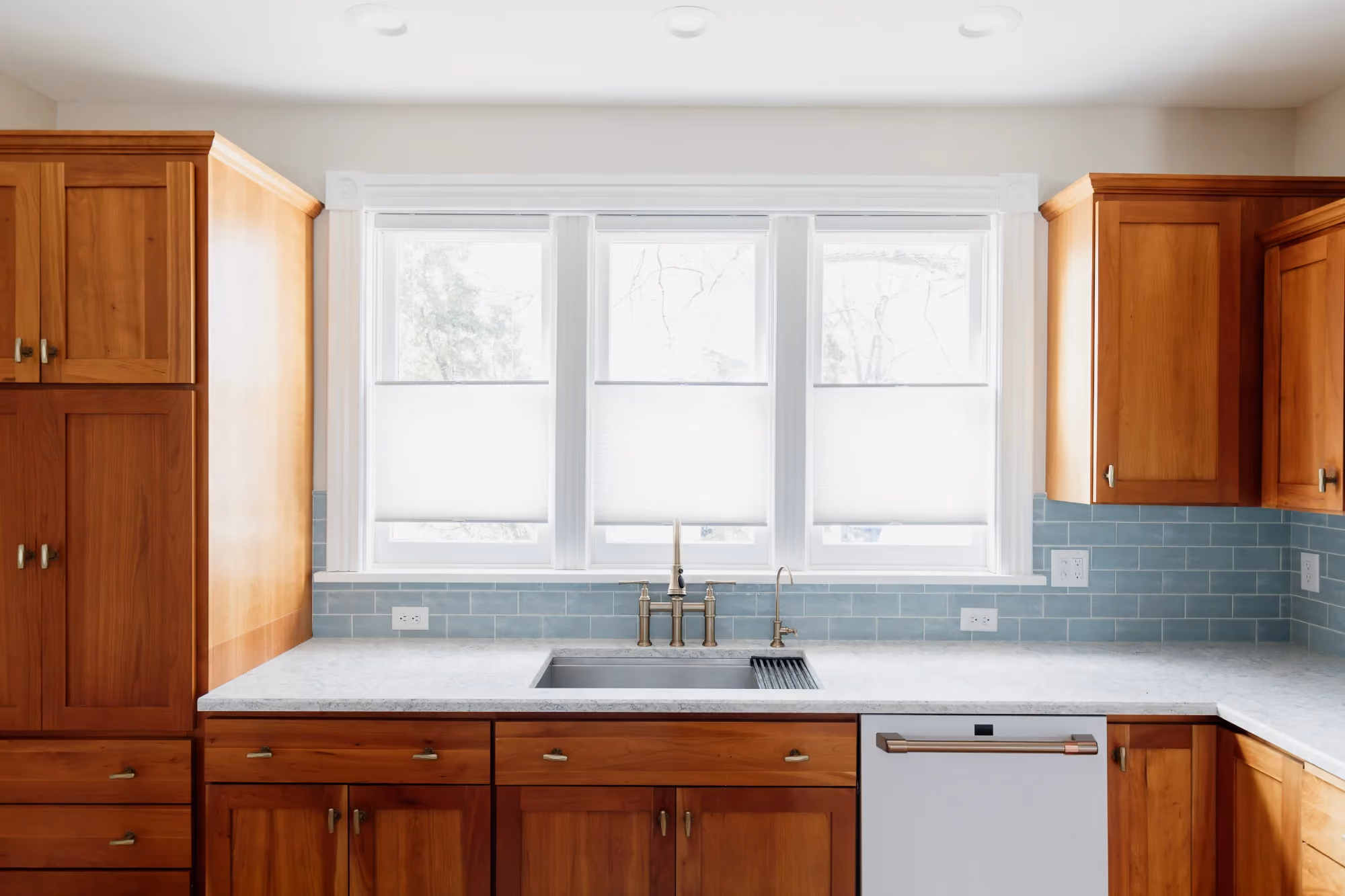 Kitchen sink under window with wooden cabinets and dishwasher
