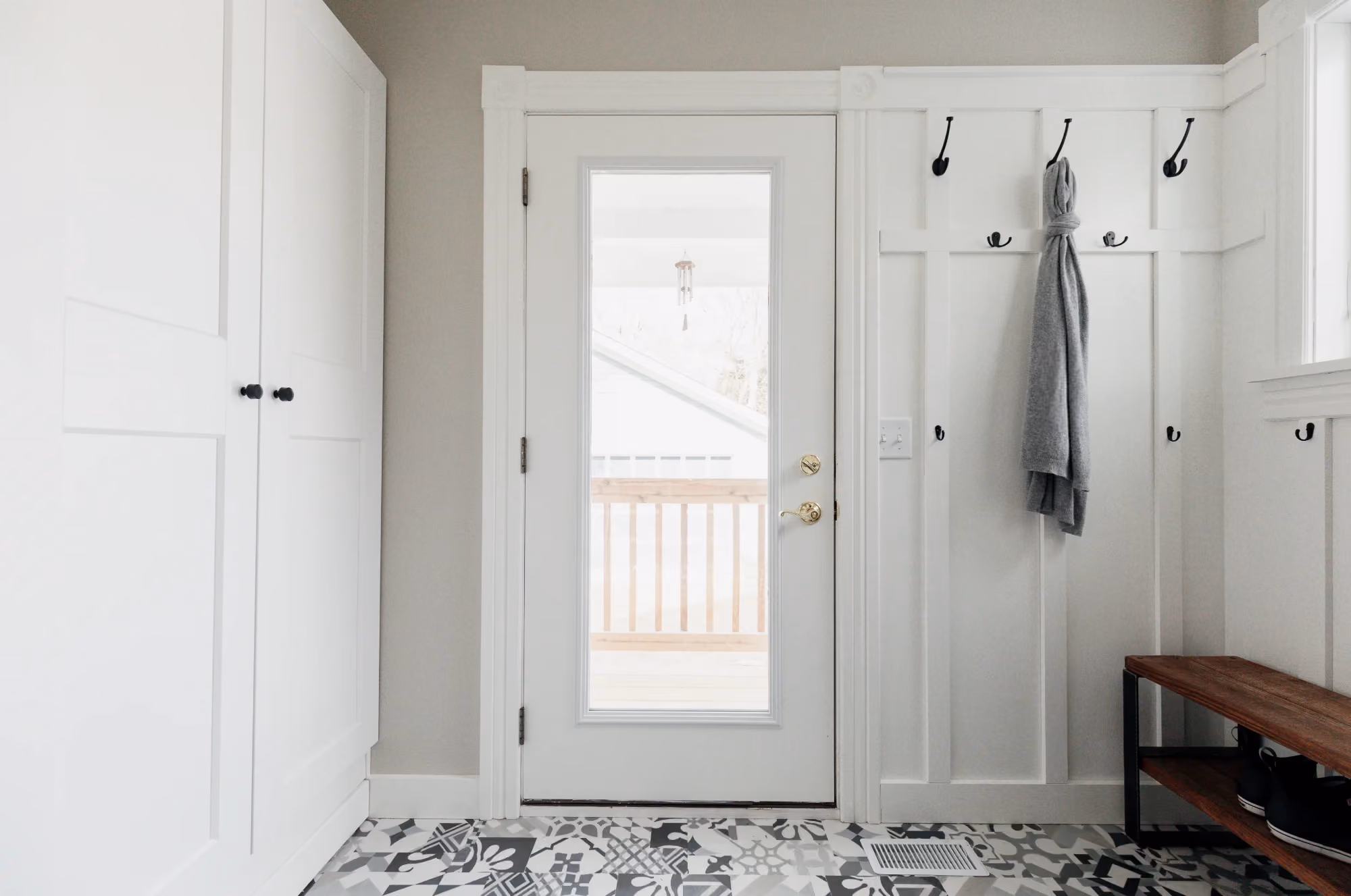 White entryway with front door and coat hooks
