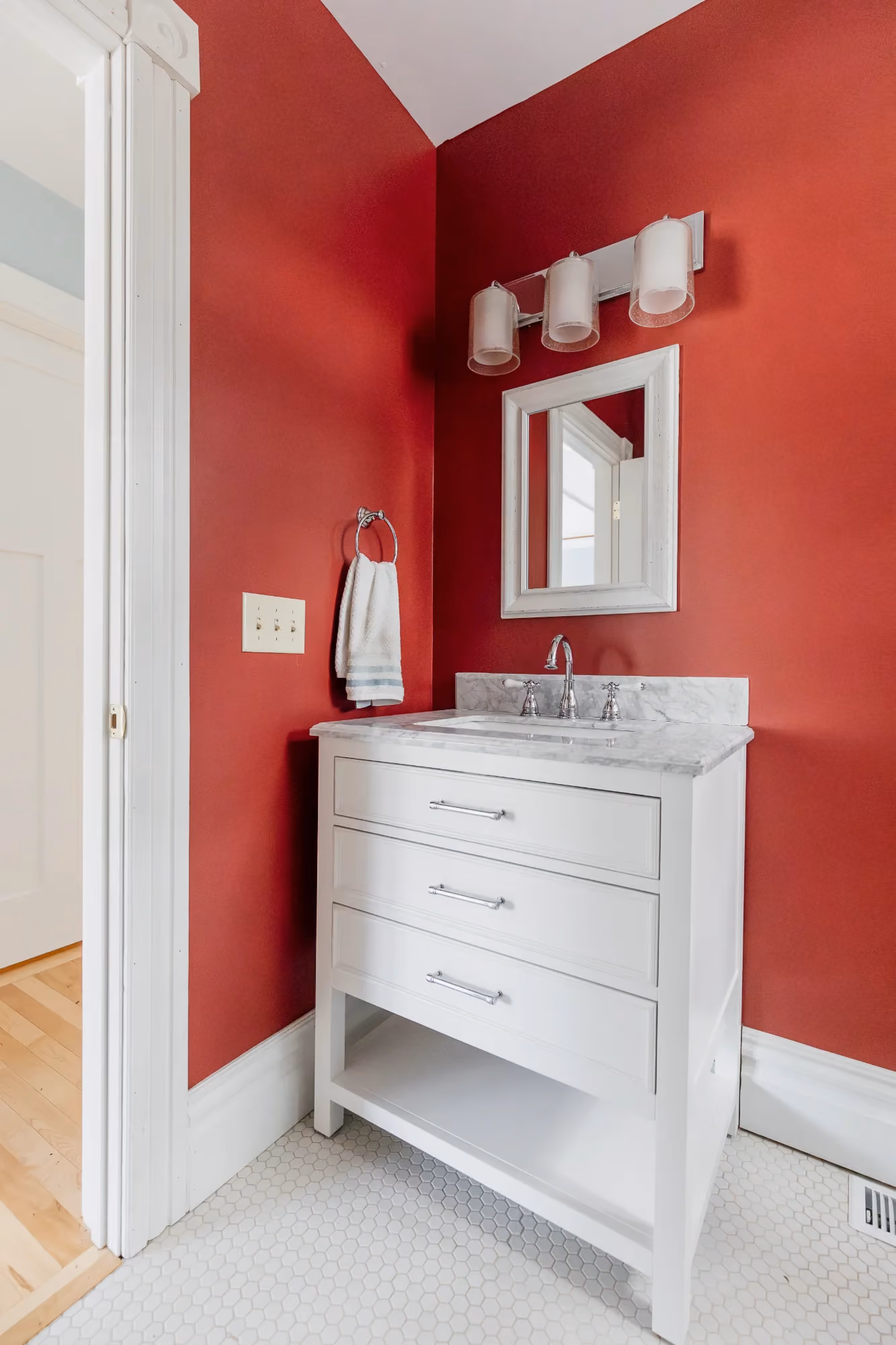 Small red powder room with white vanity and toilet