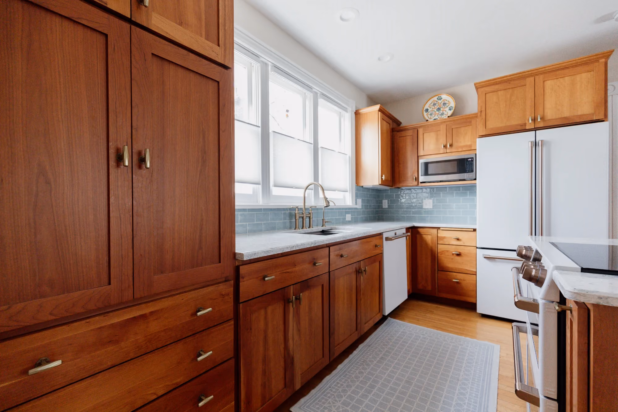 Galley kitchen with wooden cabinets and white appliances