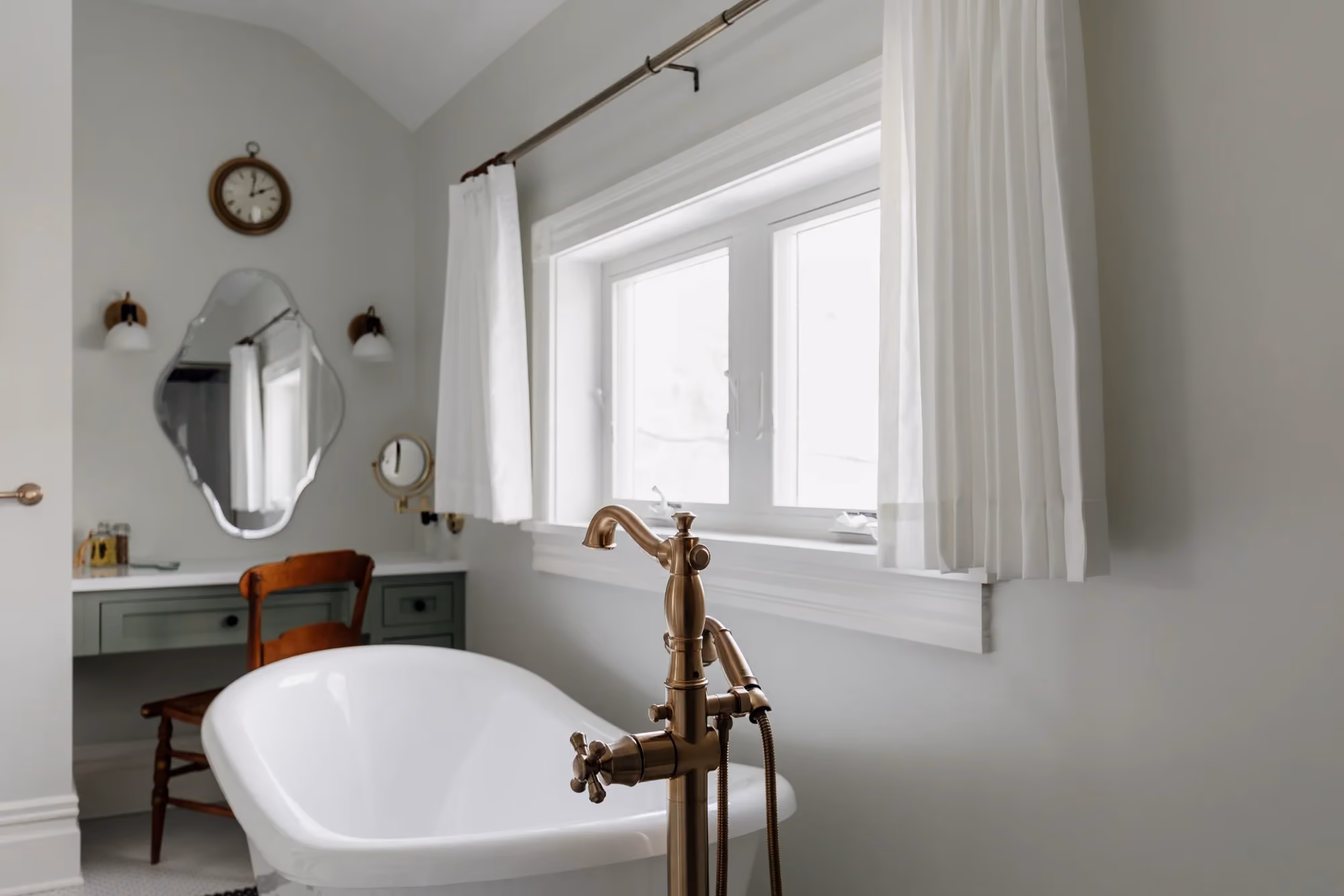 Bathroom with freestanding tub, window, and brass fixtures