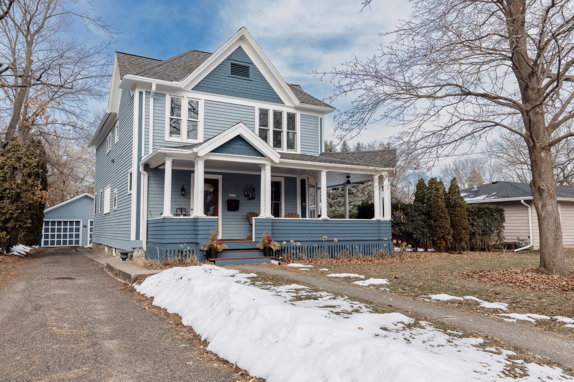 Blue two-story house exterior with driveway and snow