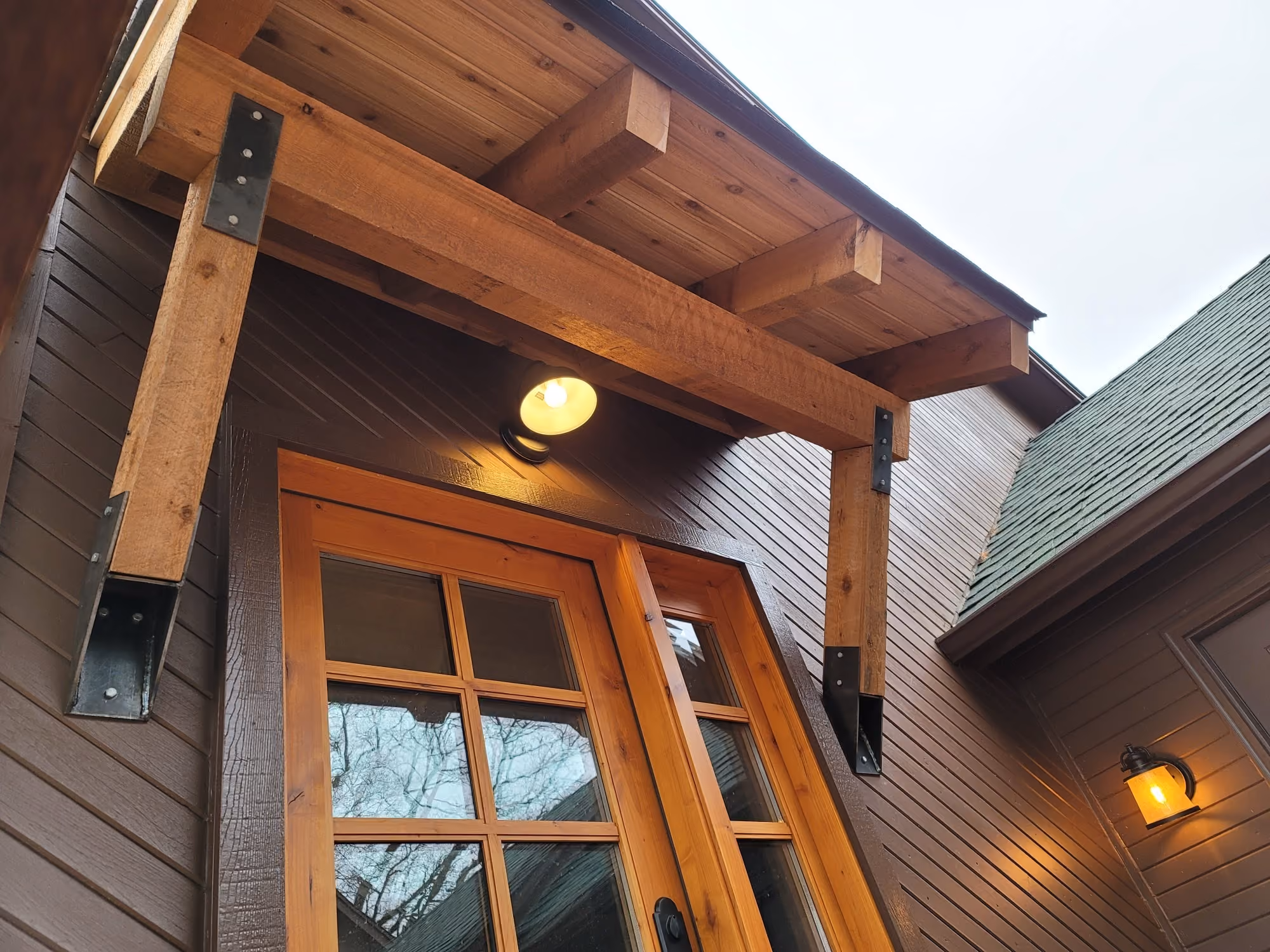 Covered porch with wooden front door and light