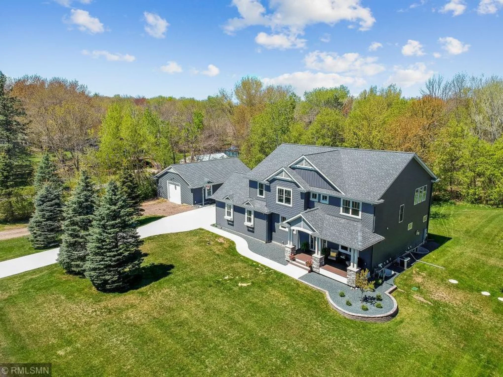 Aerial view of a large house with green lawn and trees