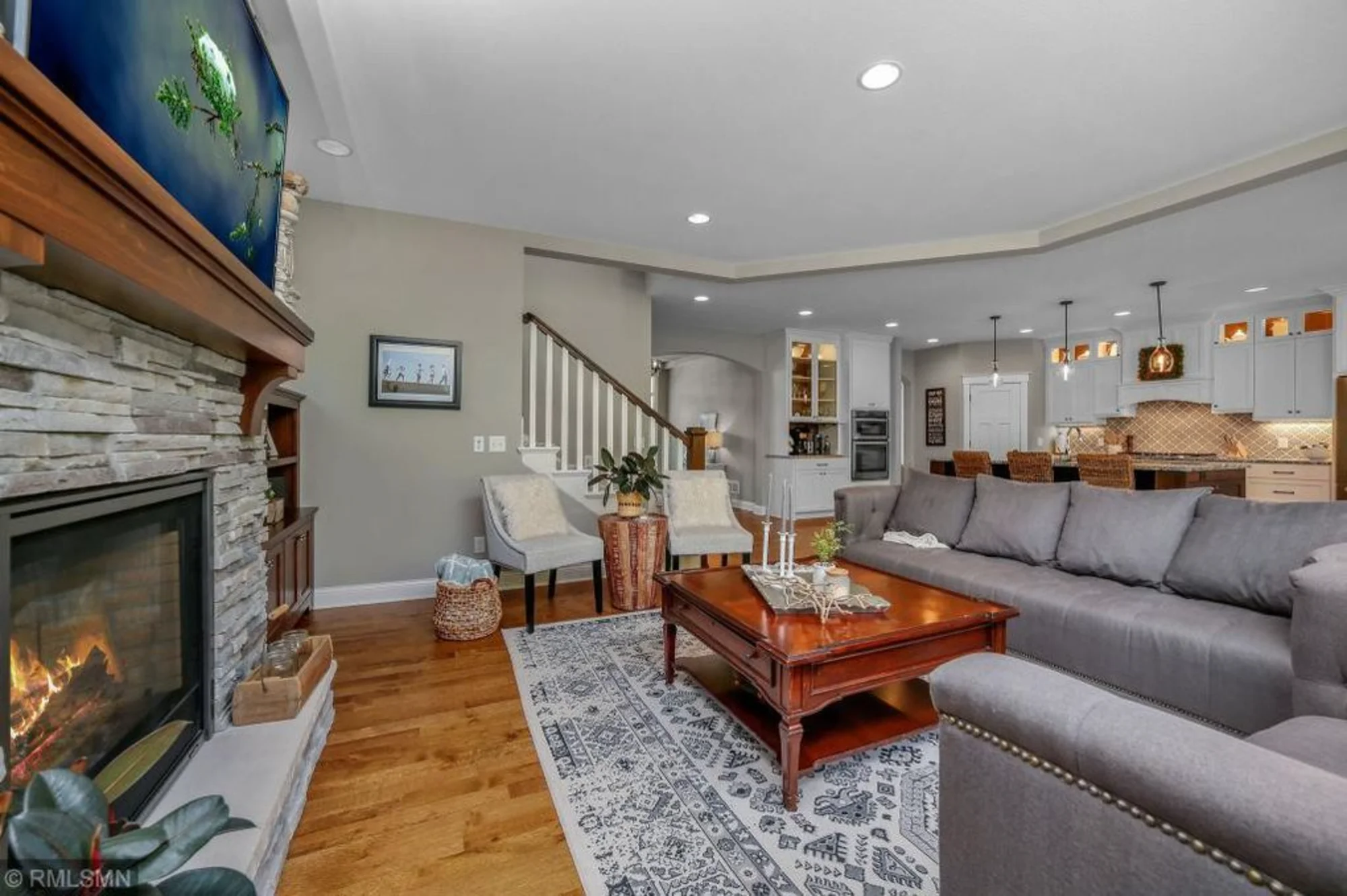 Living room with stone fireplace, sectional sofa, and wood floors