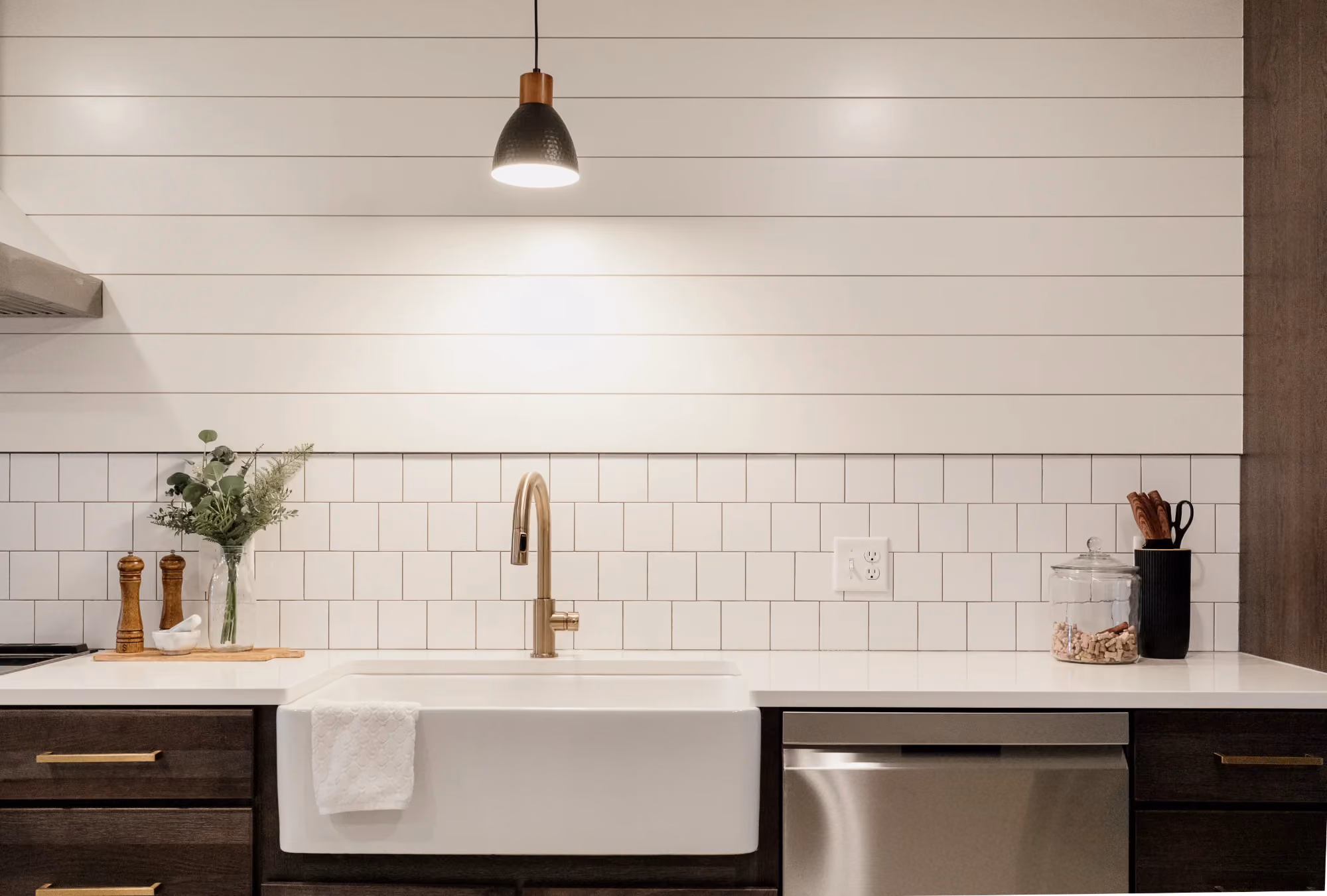 Farmhouse kitchen sink with brass faucet and white shiplap wall