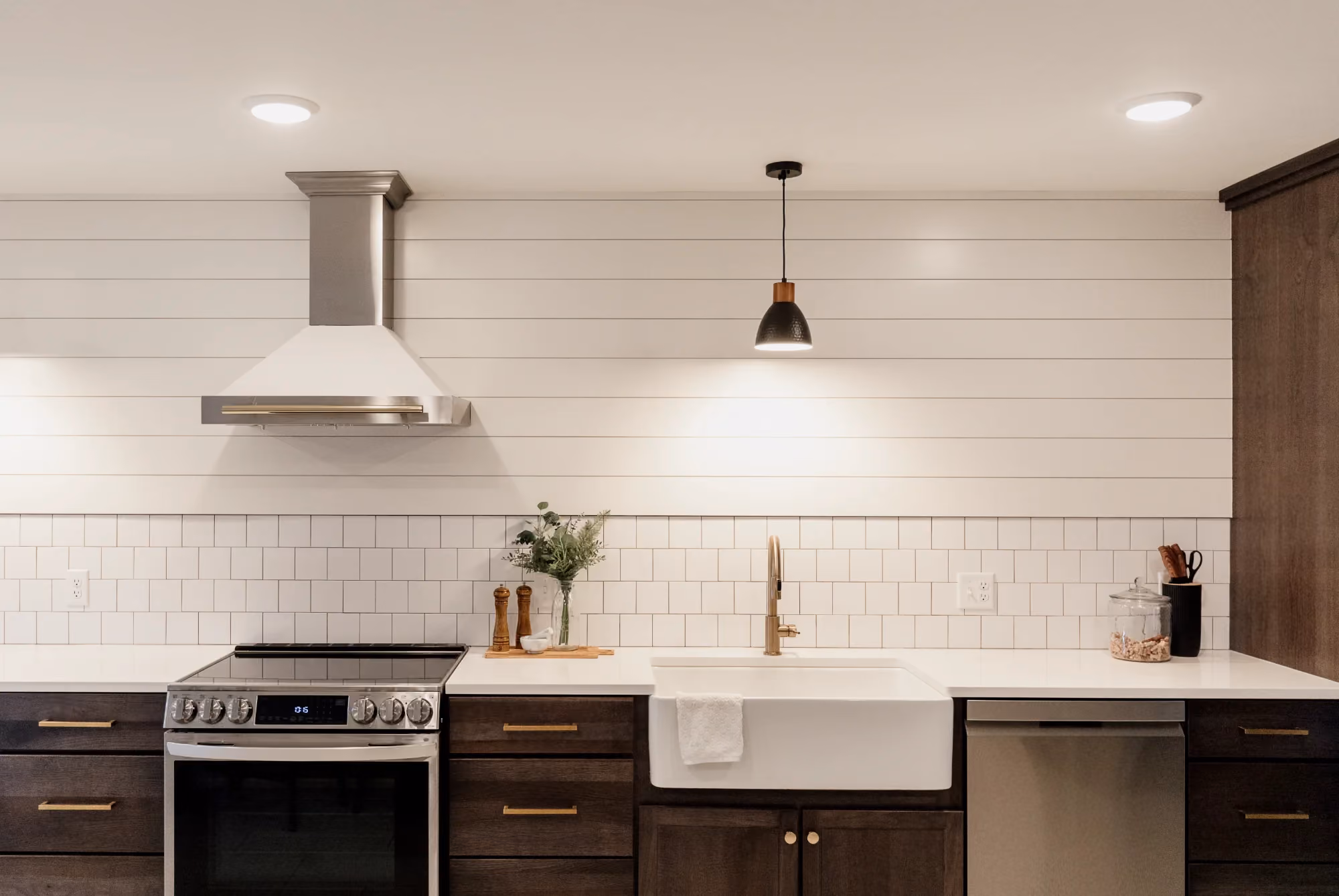 Kitchen range and farmhouse sink with shiplap backsplash and pendant lights