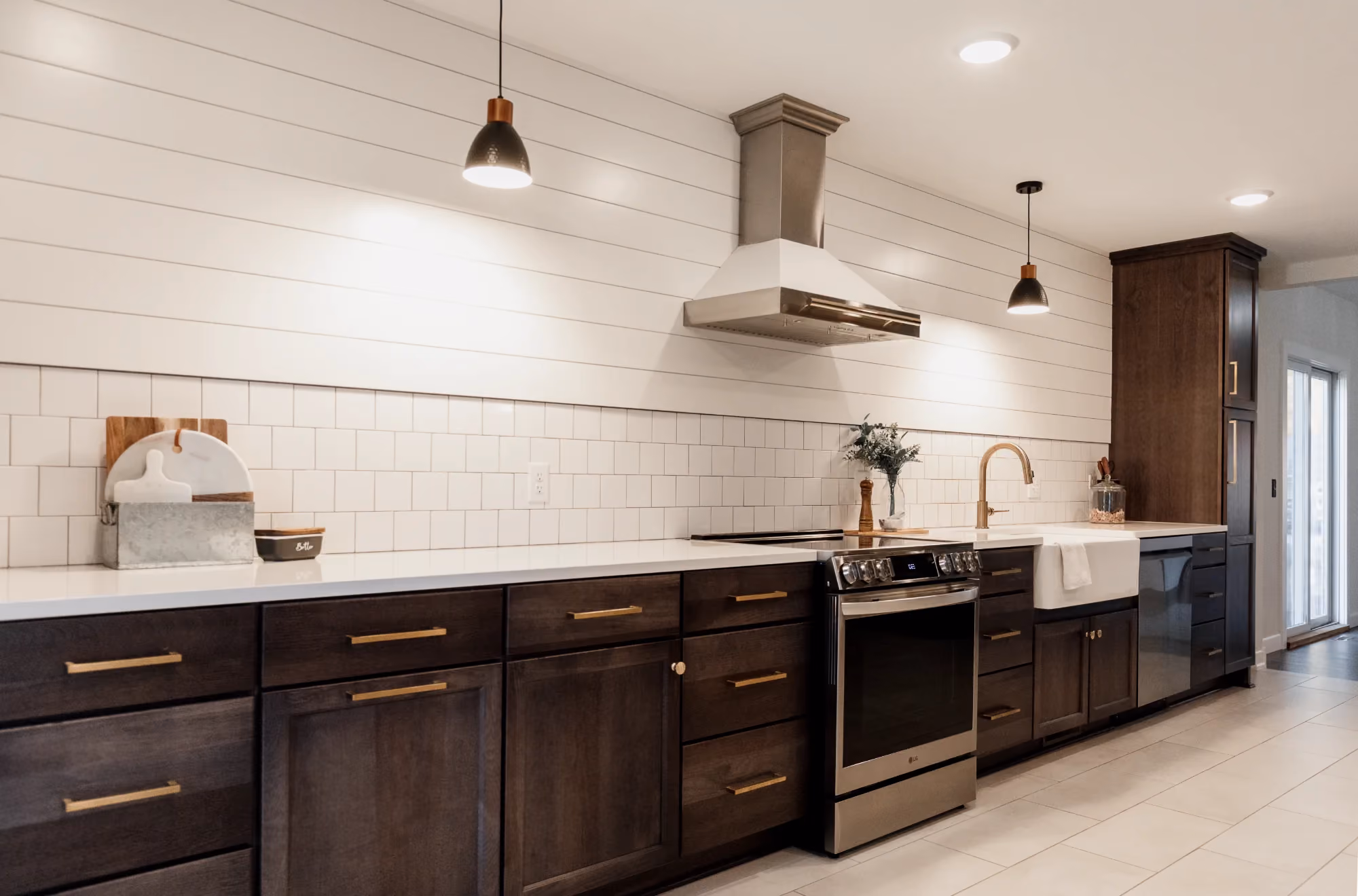 Kitchen with dark cabinets, white shiplap, and stainless range hood