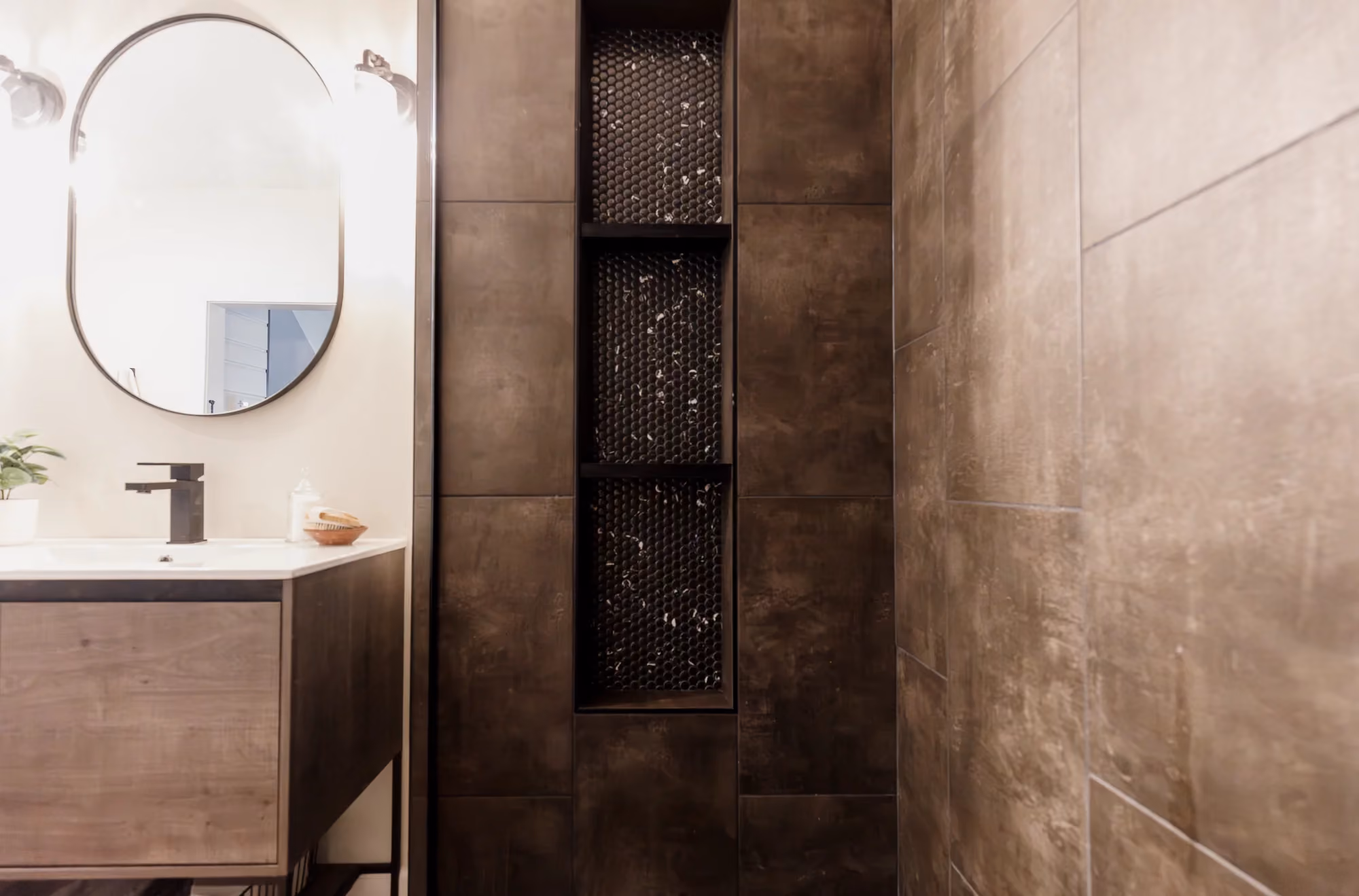 Bathroom vanity with round mirror and tiled shower