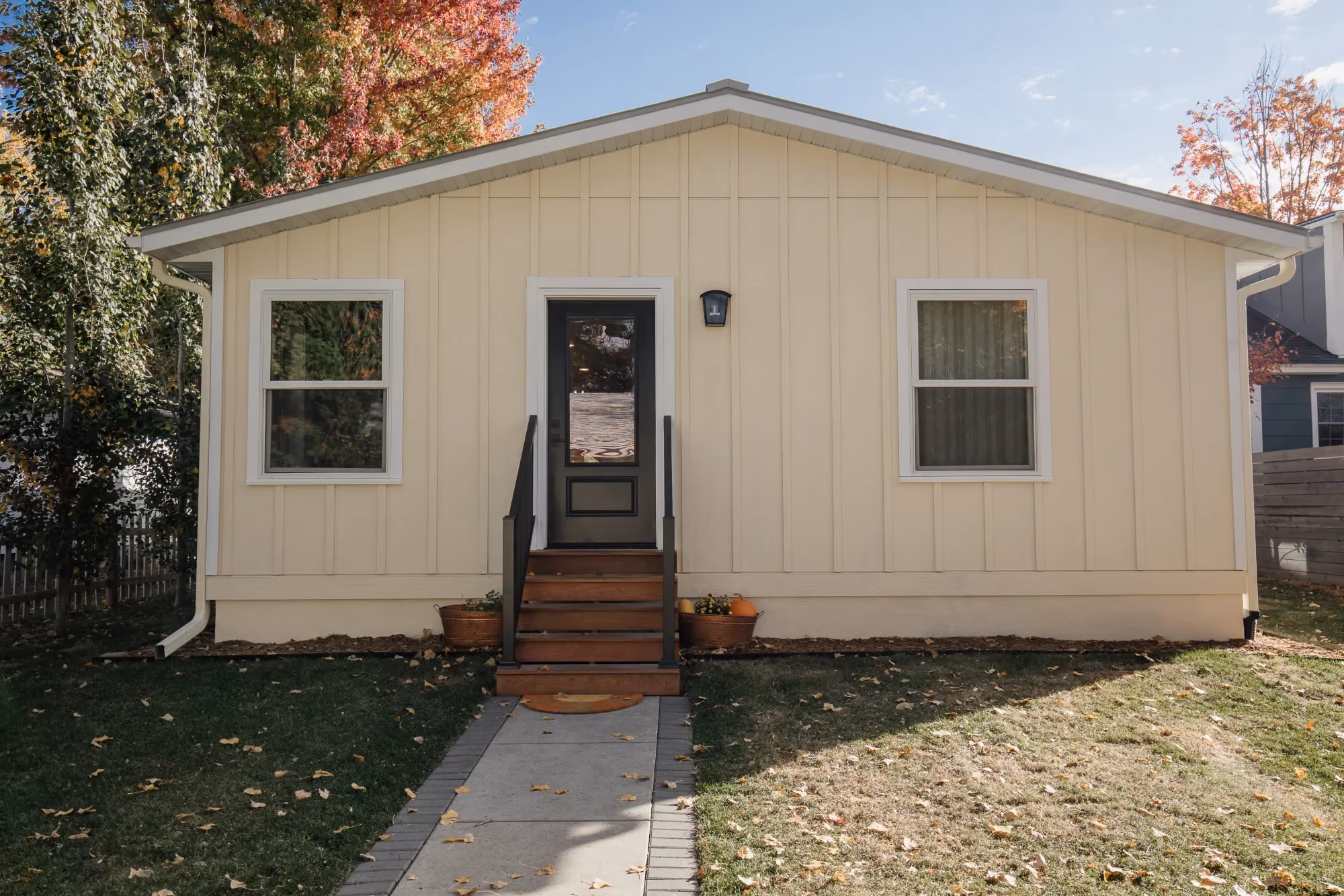 Small beige cottage exterior with front steps and walkway