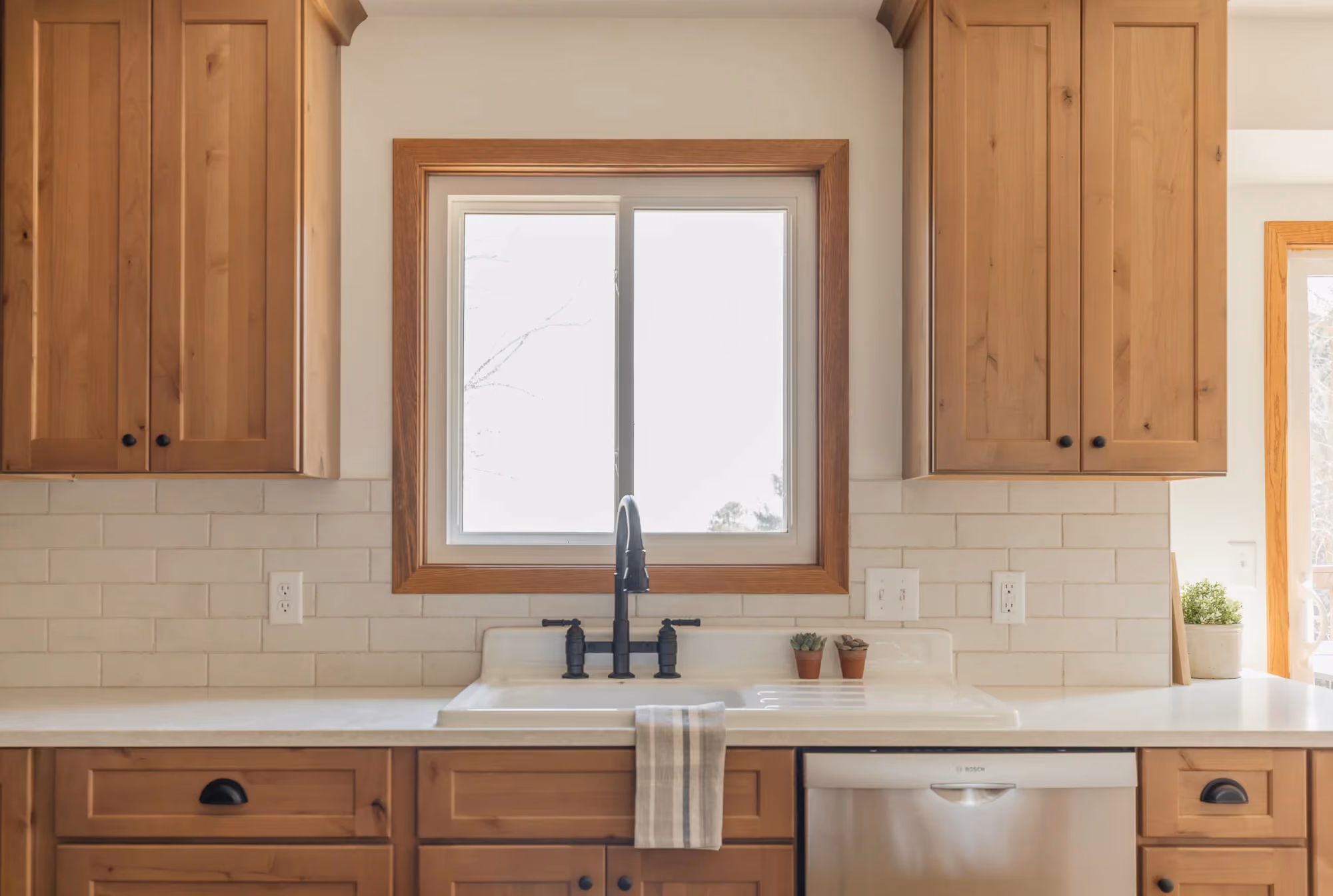 Kitchen sink under window with wood cabinetry