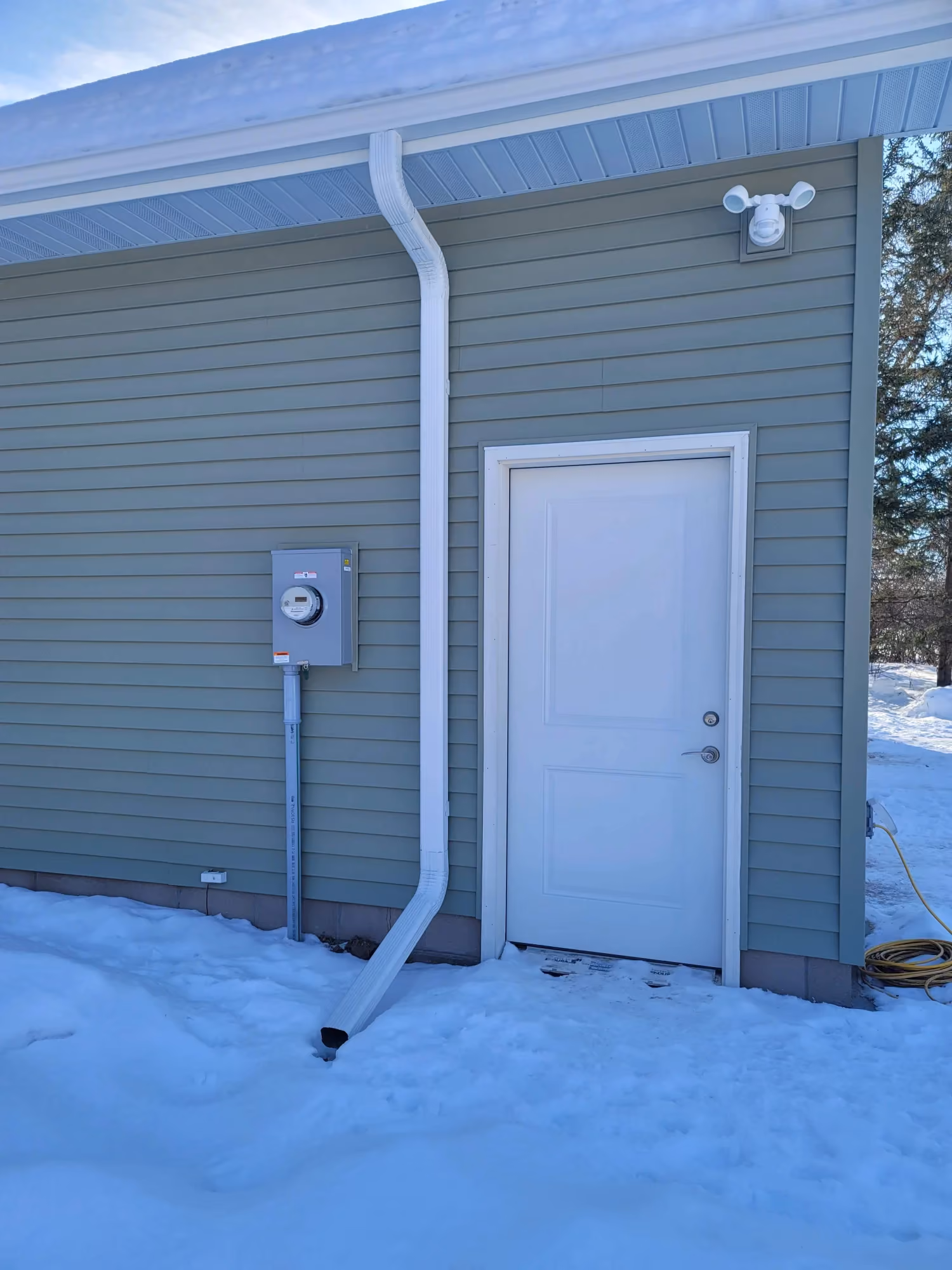 White exterior door with steps and utility meter in snow