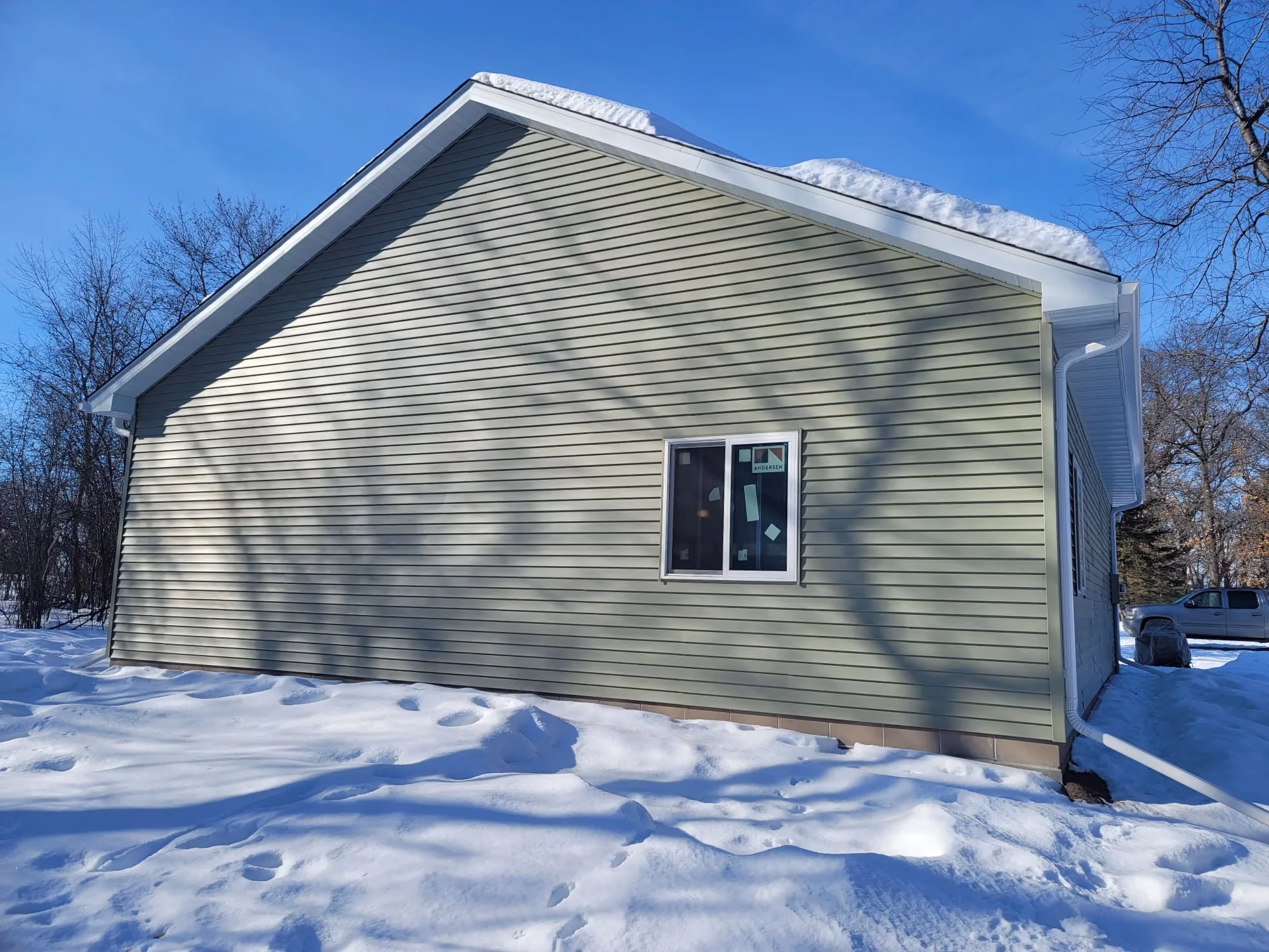 Gray shed exterior with window in snowy yard
