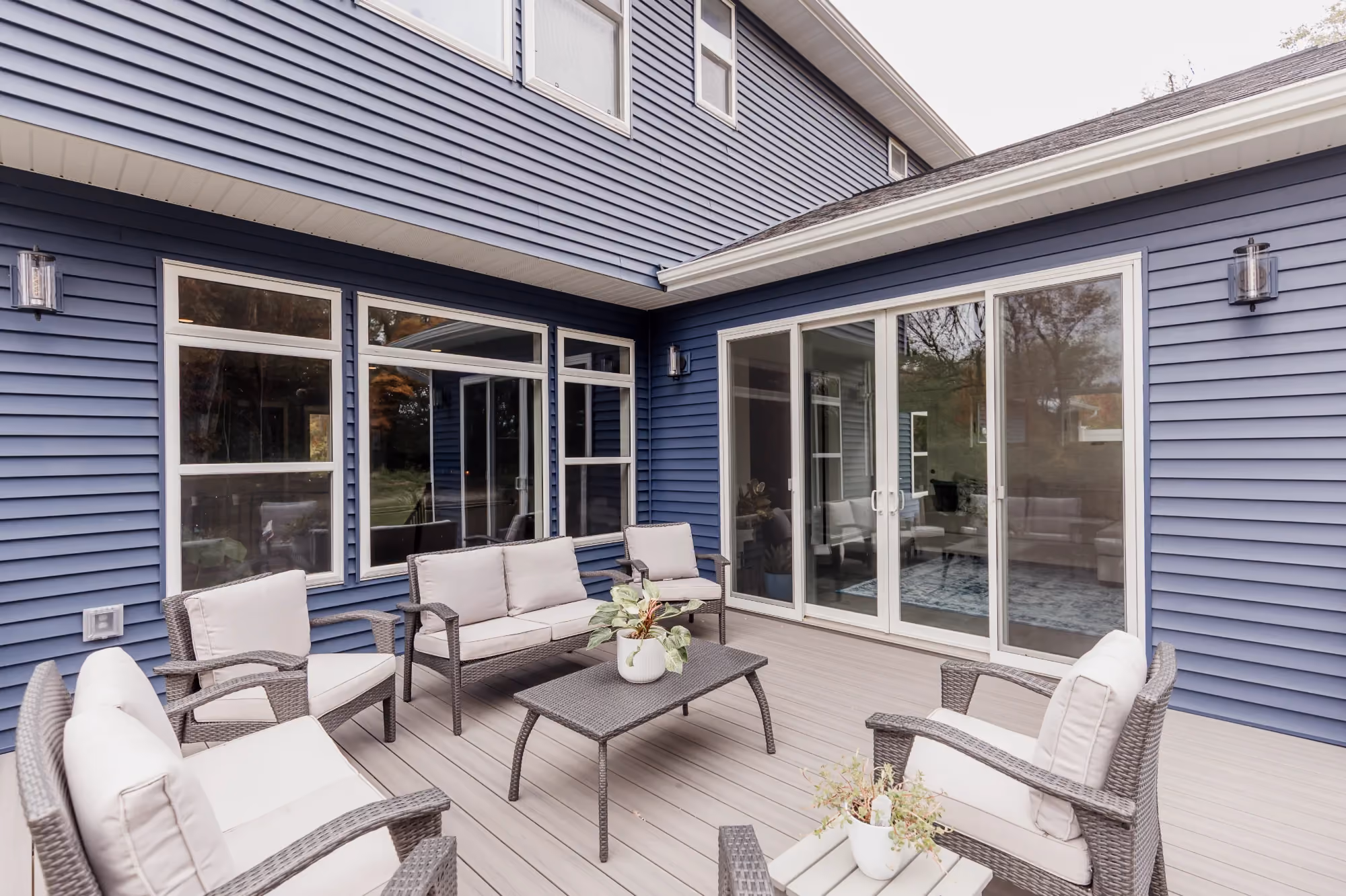 Outdoor patio with seating beside a blue house