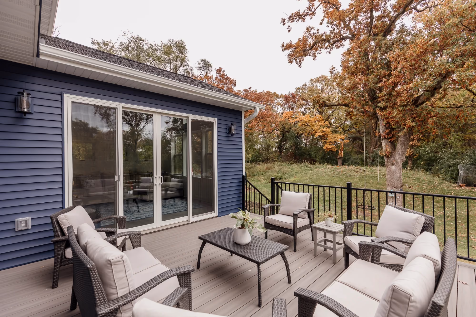 Deck seating area beside house with fall trees