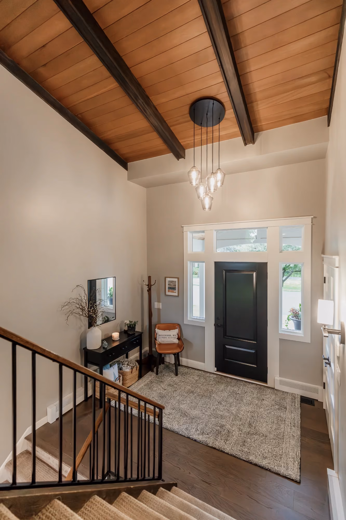 Stair landing with wood ceiling and railing overlooking entry