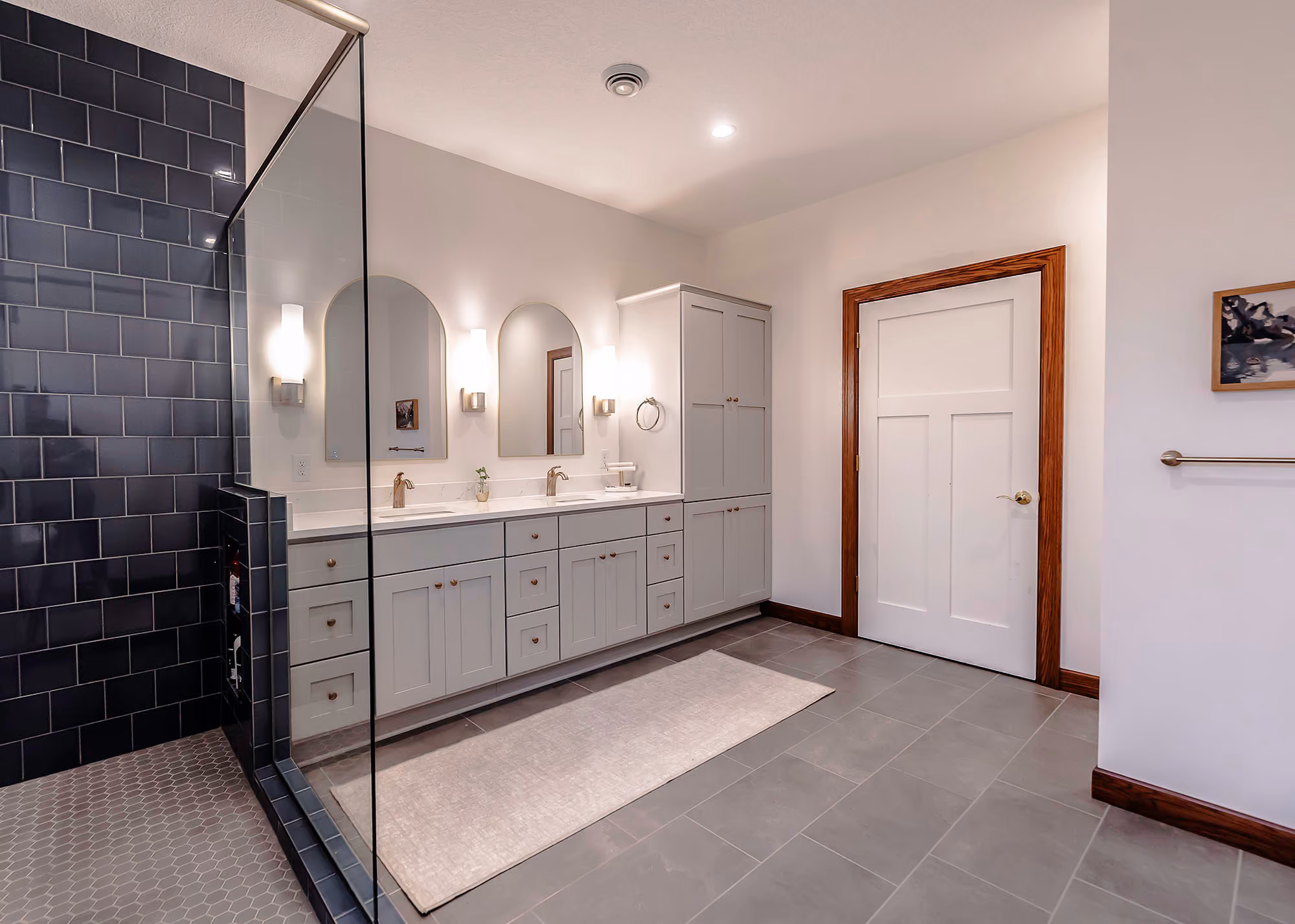 Bathroom with dark tiled shower and double vanity