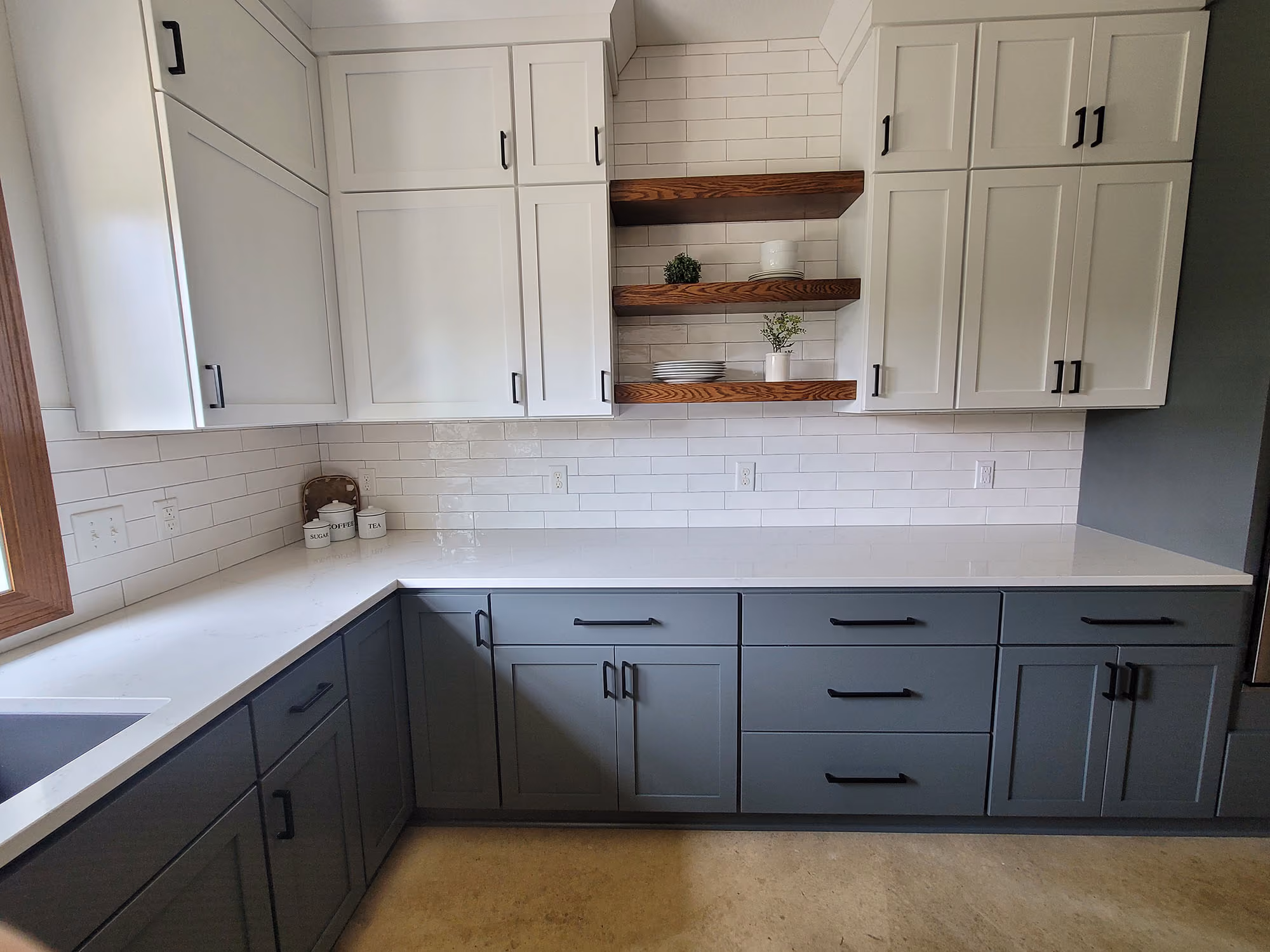 Corner view of gray-and-white kitchen cabinetry and open shelves